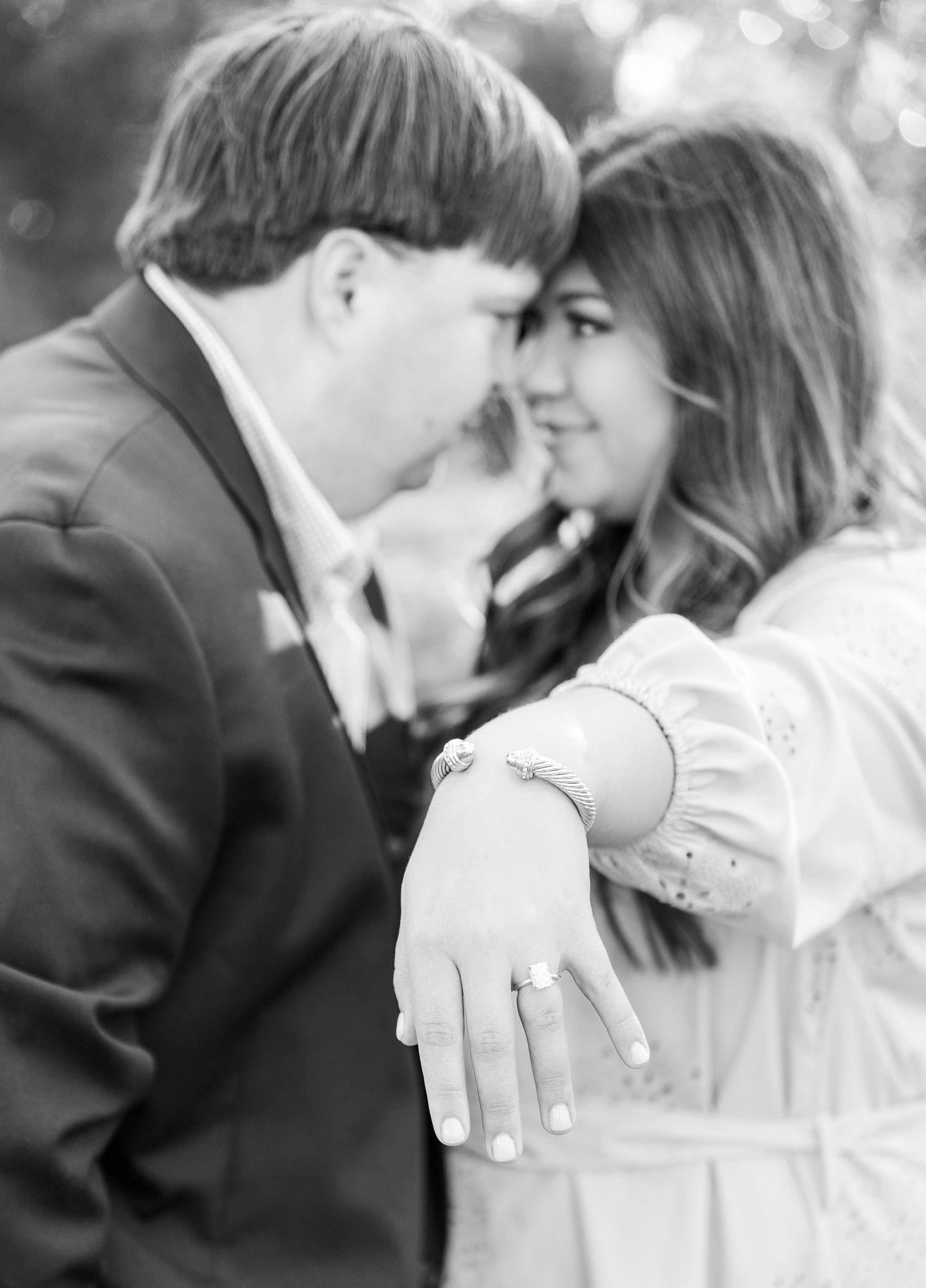 A romantic black and white engagement photo shows a couple sharing an intimate moment.