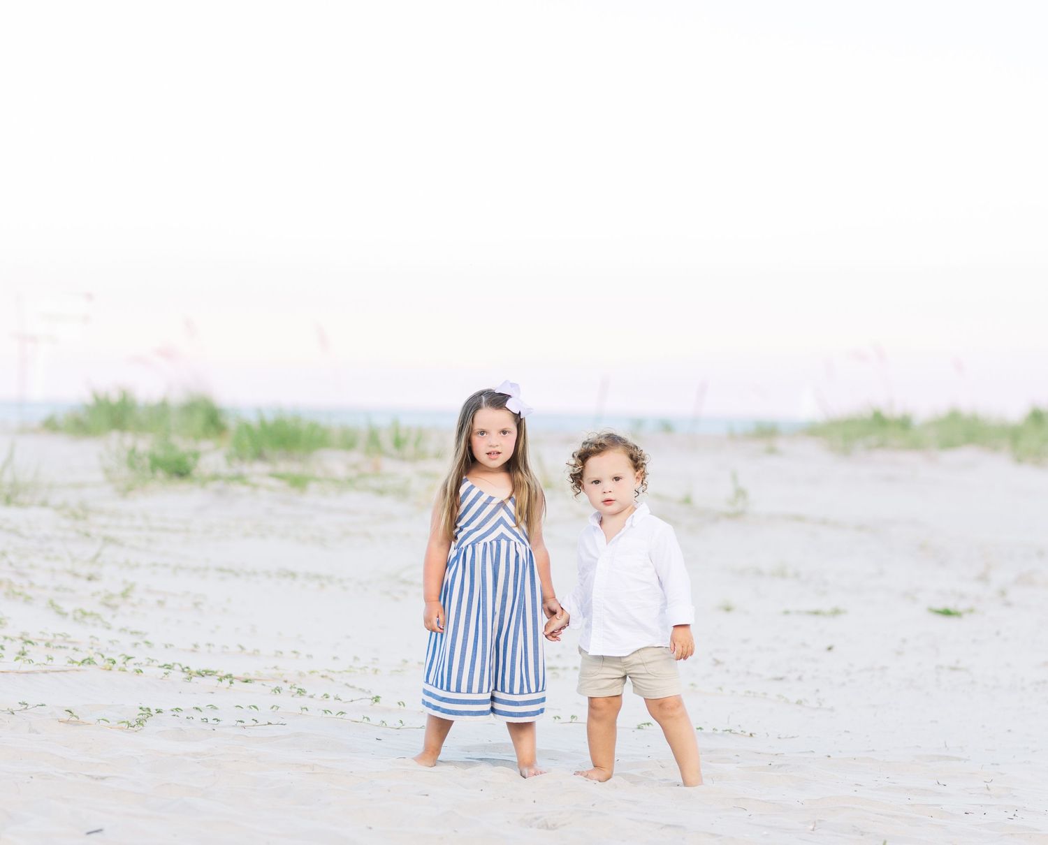 Children in coordinating blue and white outfits playing on a serene beach landscape.