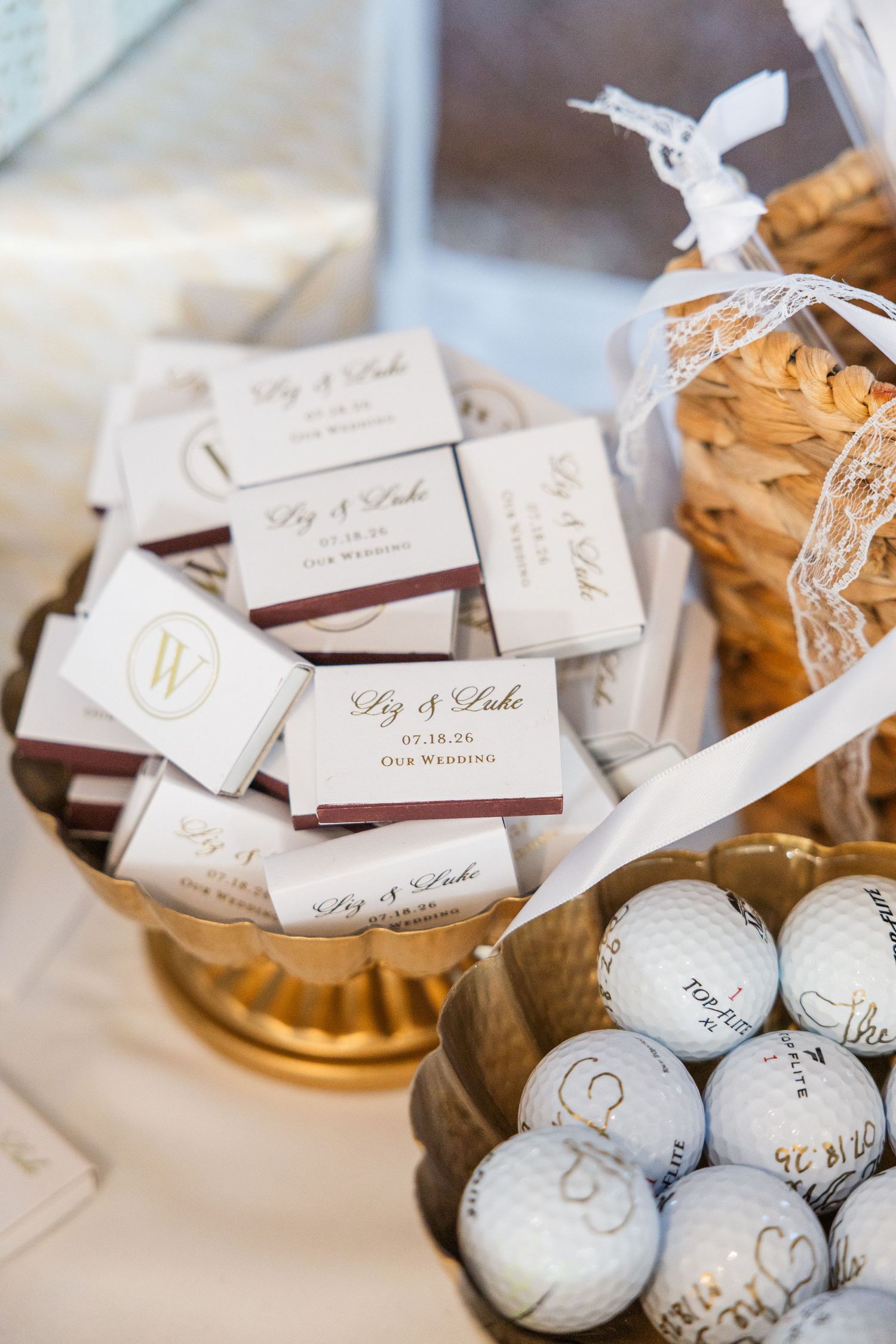 Elegant wedding favors display with personalized matchboxes and golf balls in gold bowls for Liz and Luke's wedding.