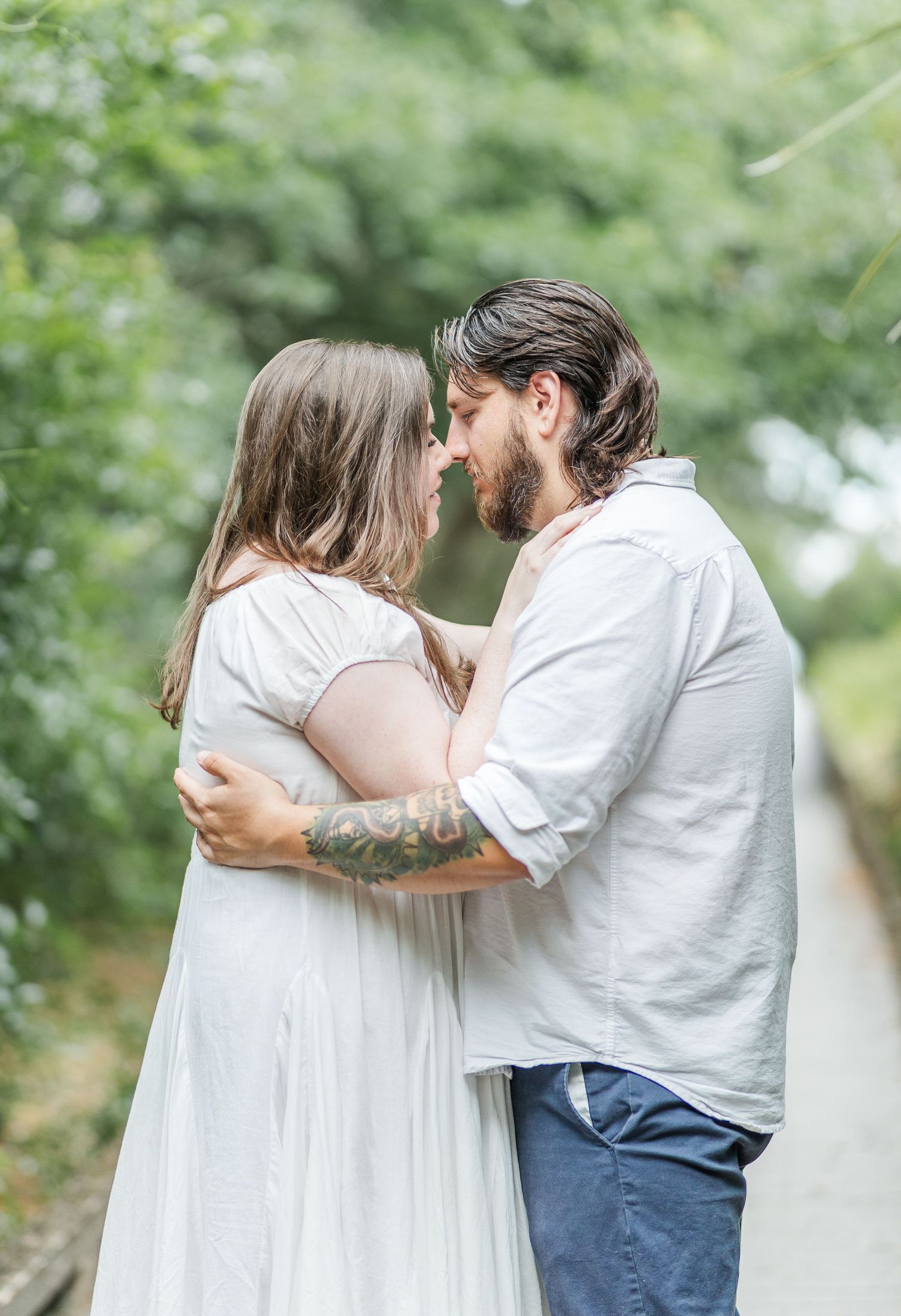 Tender moment between a couple in white clothing surrounded by green garden scenery.