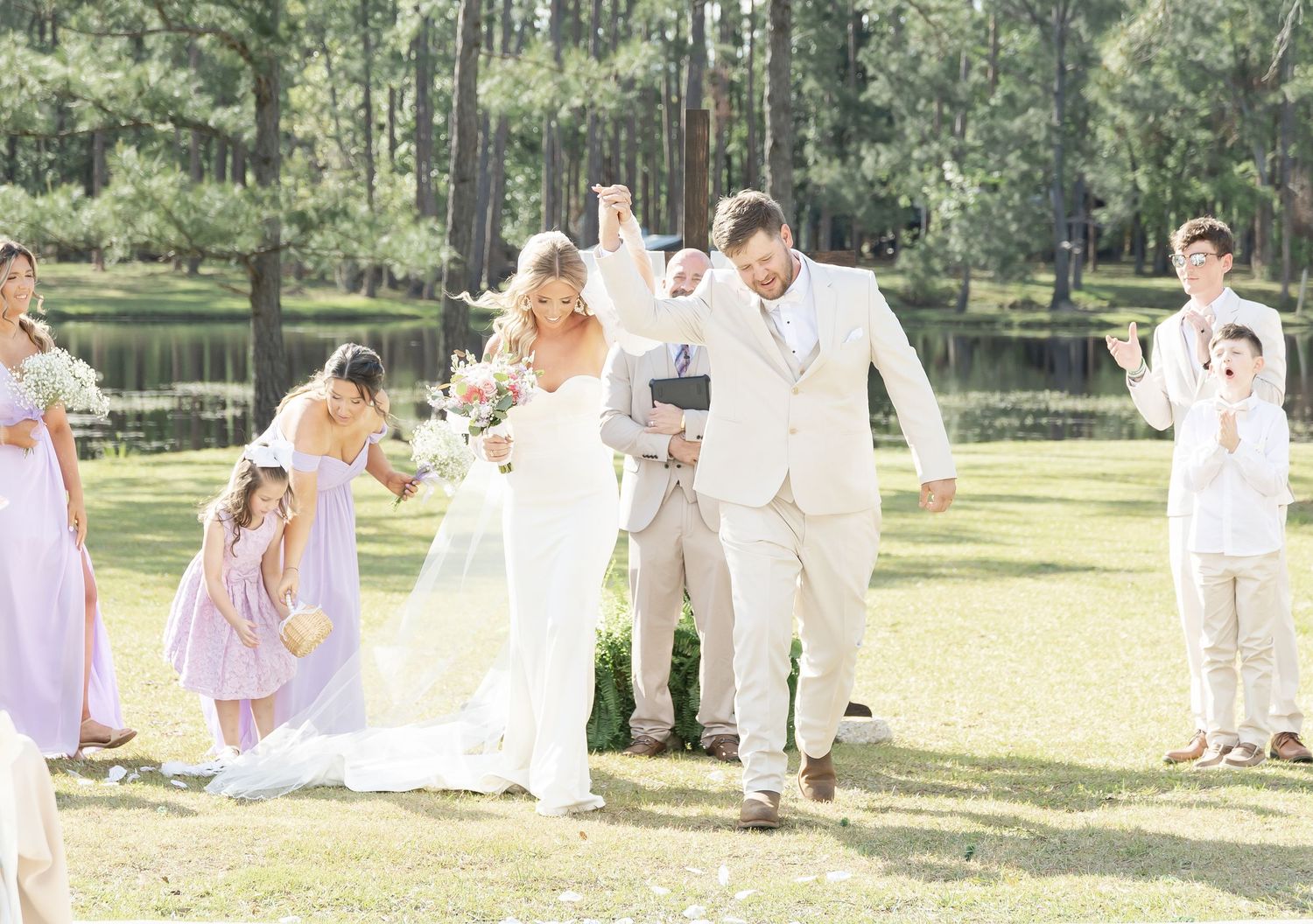 Wedding celebration in a forest setting with bridesmaids in lavender dresses and elegant white decor.