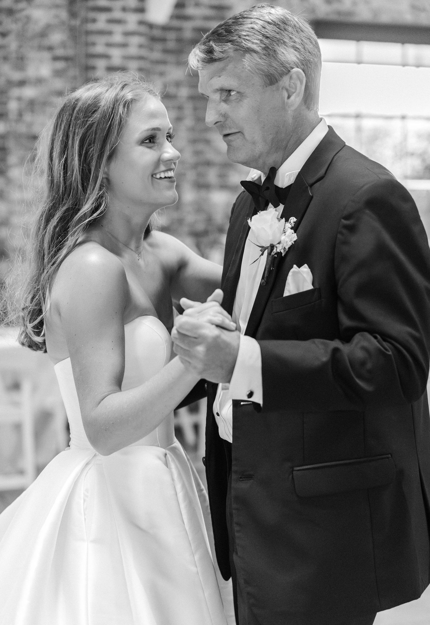 Black and white photo of bride and father sharing emotional father-daughter dance at wedding.