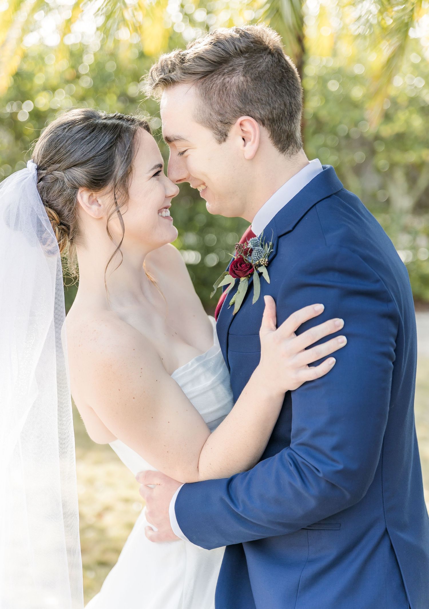 A tender romantic moment between newlyweds outdoors with the bride in white and groom in navy blue on their wedding day.