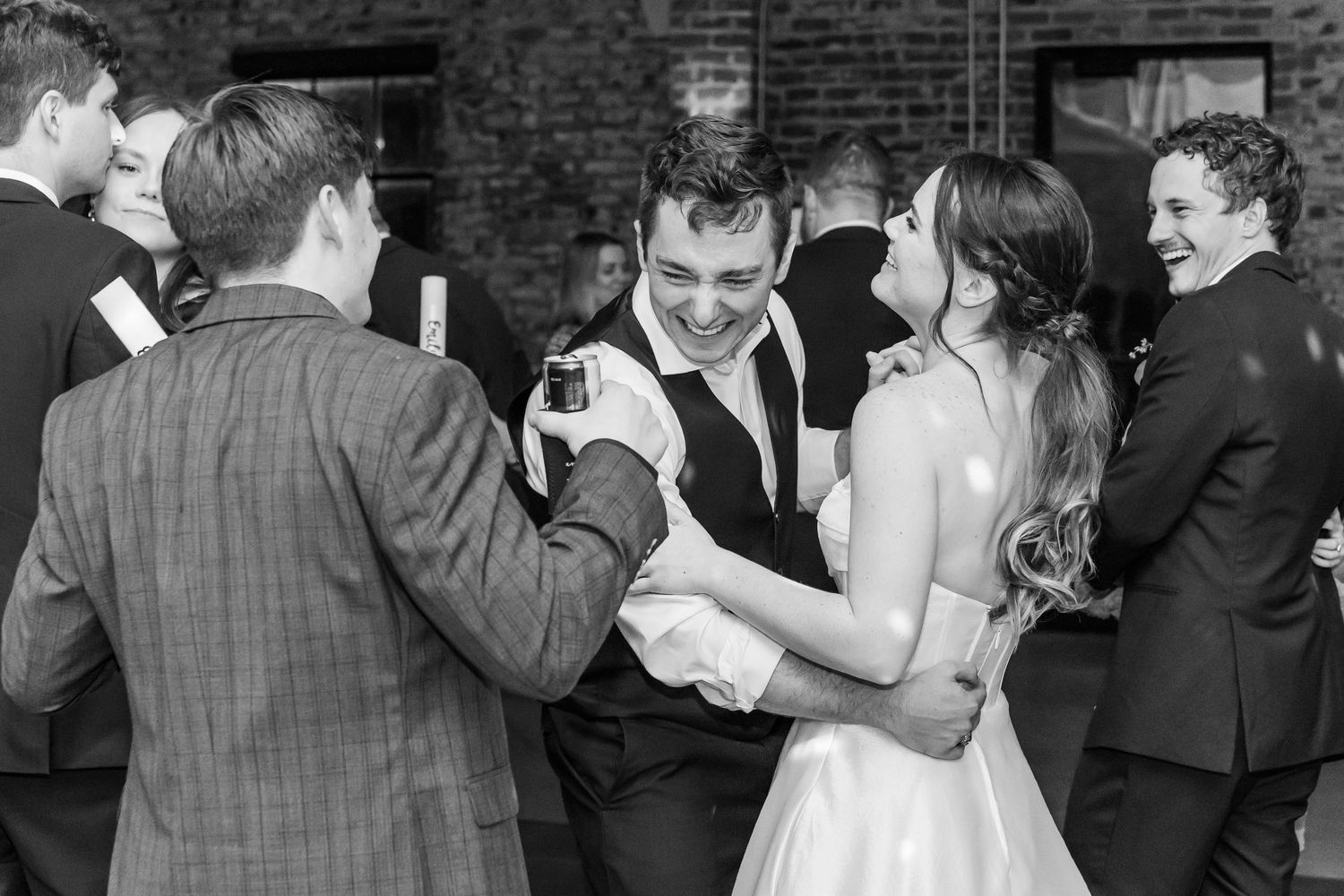 Black and white photo collage showing emotional moments during a wedding celebration with dancing and embraces.