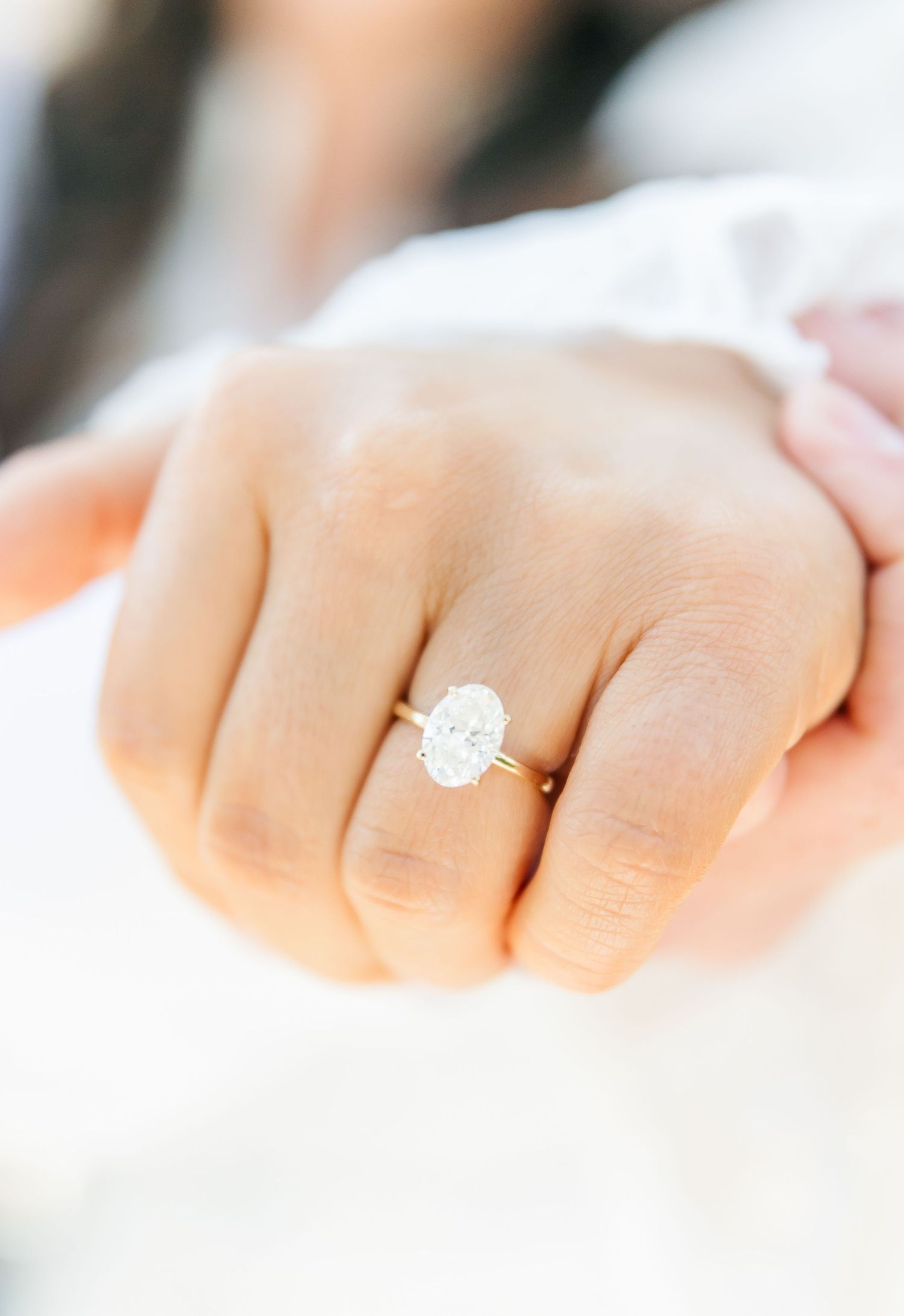 Close up shot of a diamond engagement ring on a hand with soft focus background.