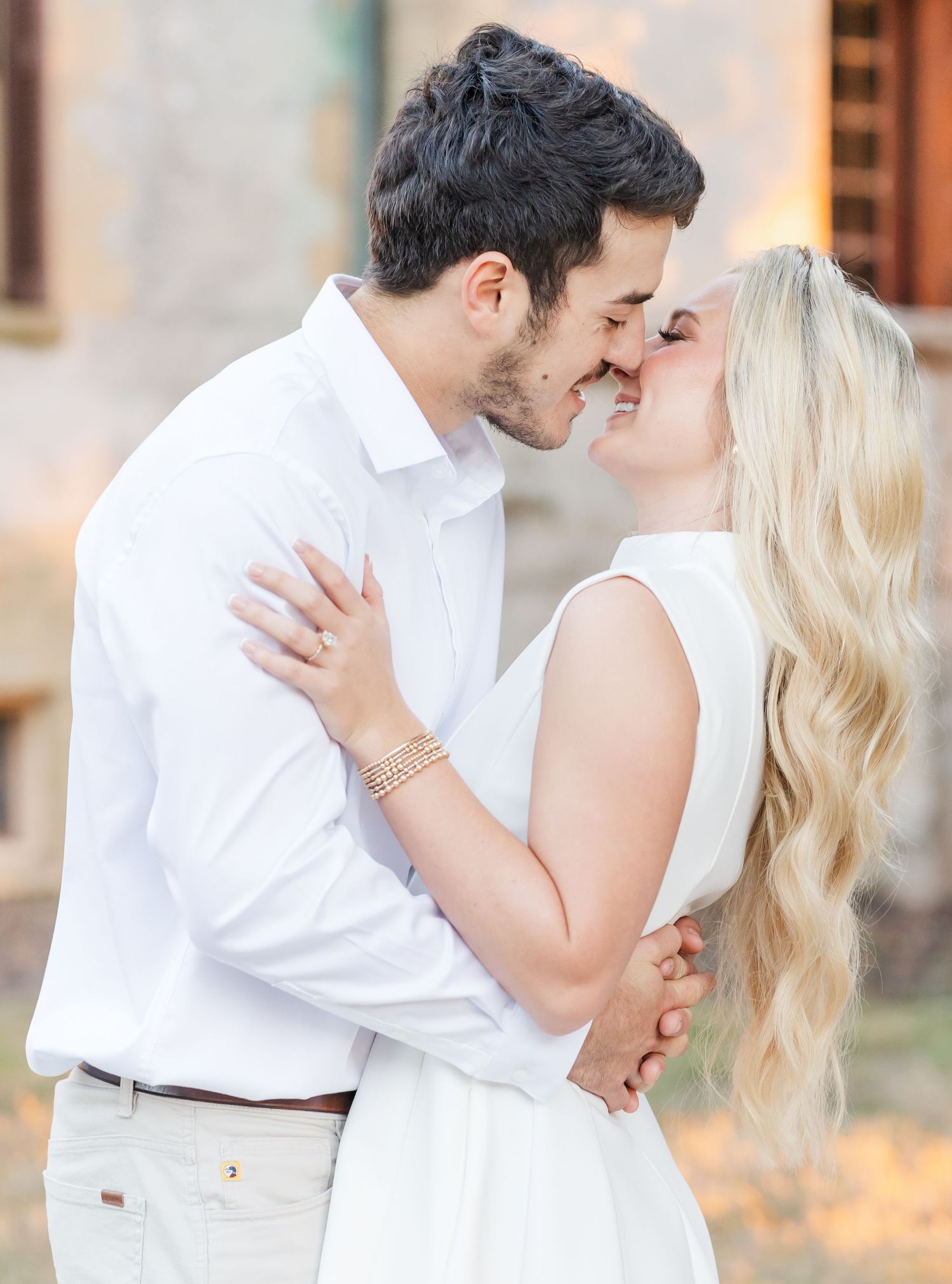 A romantic couple embraces during a sunset engagement photo session in warm golden lighting.