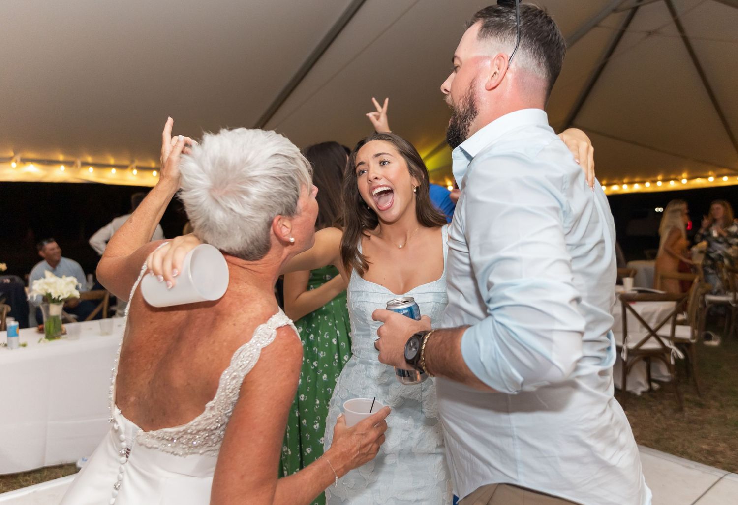 Guests celebrating and dancing together at a lively wedding reception under string lights.