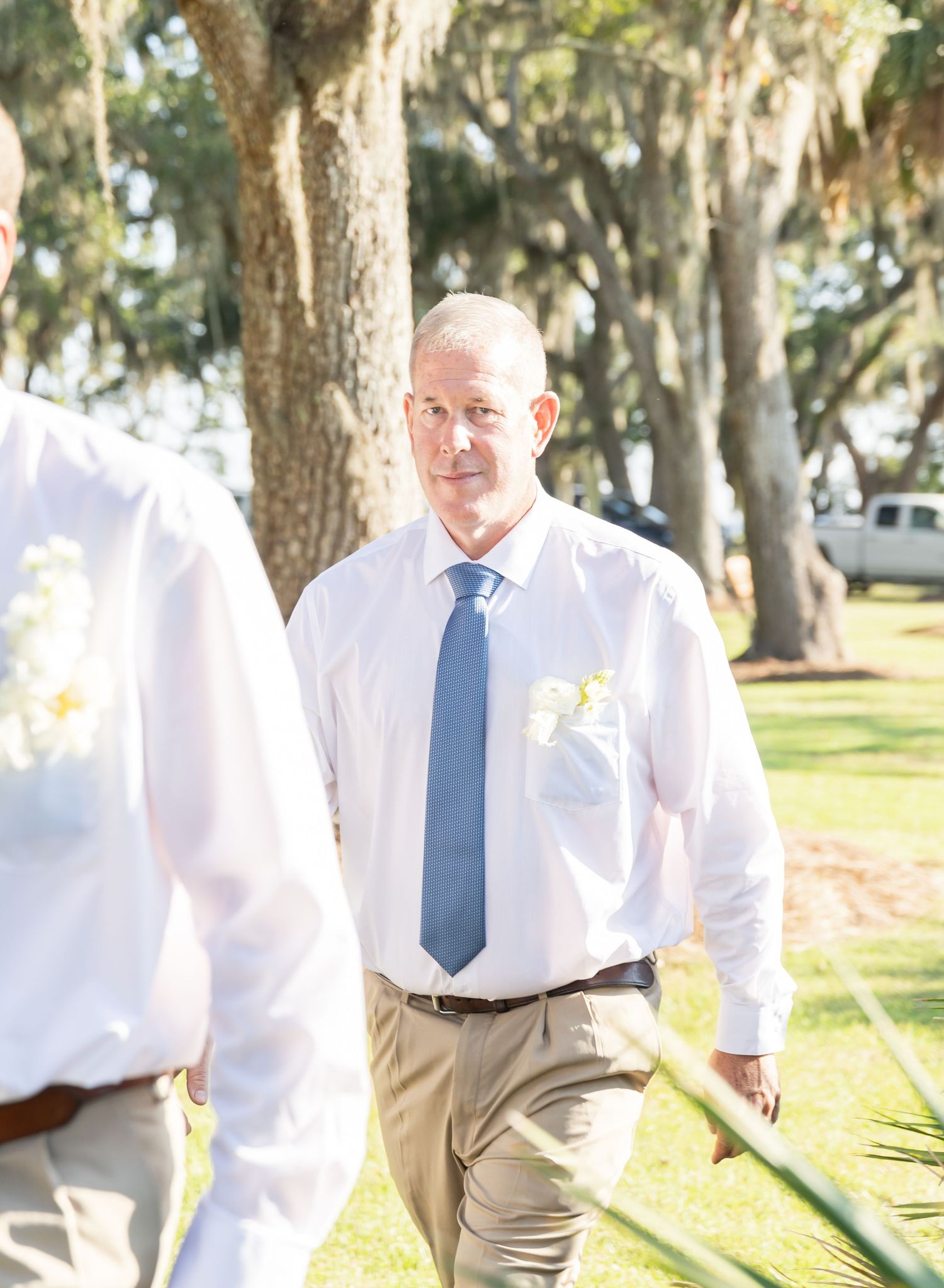 A series of candid outdoor photos showing someone in a white dress shirt and blue tie walking in a park setting.