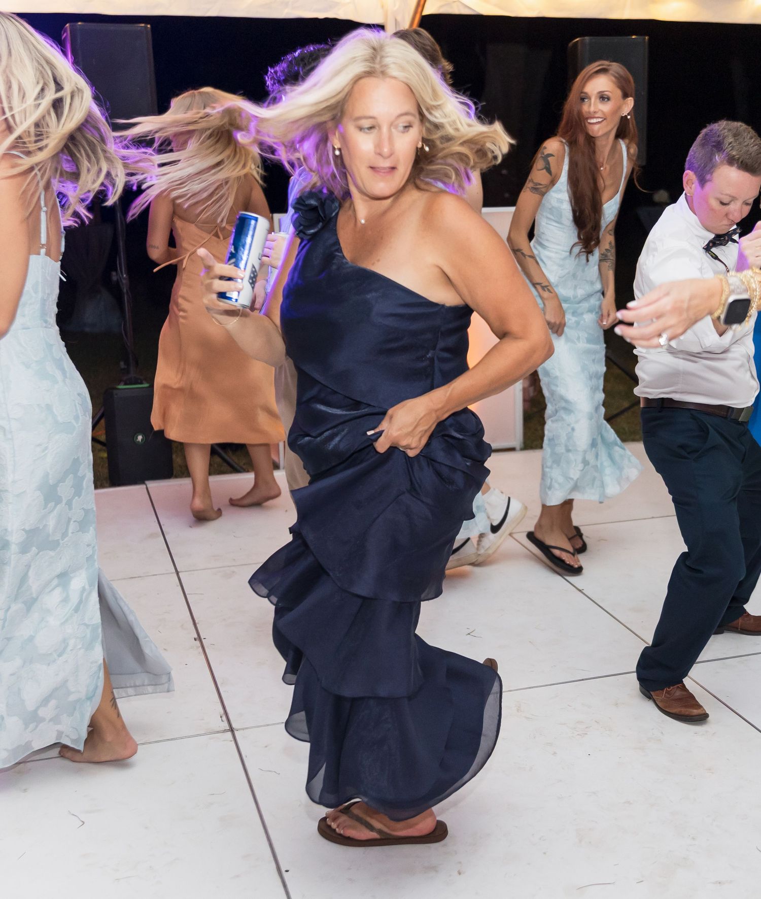 People dancing and having fun on a white dance floor at a wedding reception.