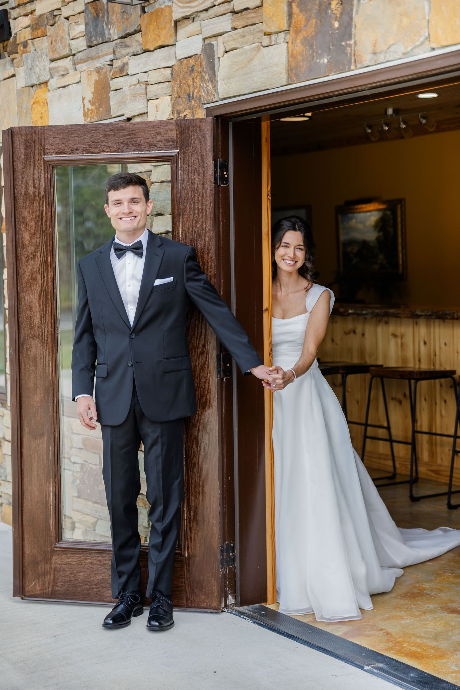 Wedding couple playfully poses in doorways of stone building during their first look photo session.