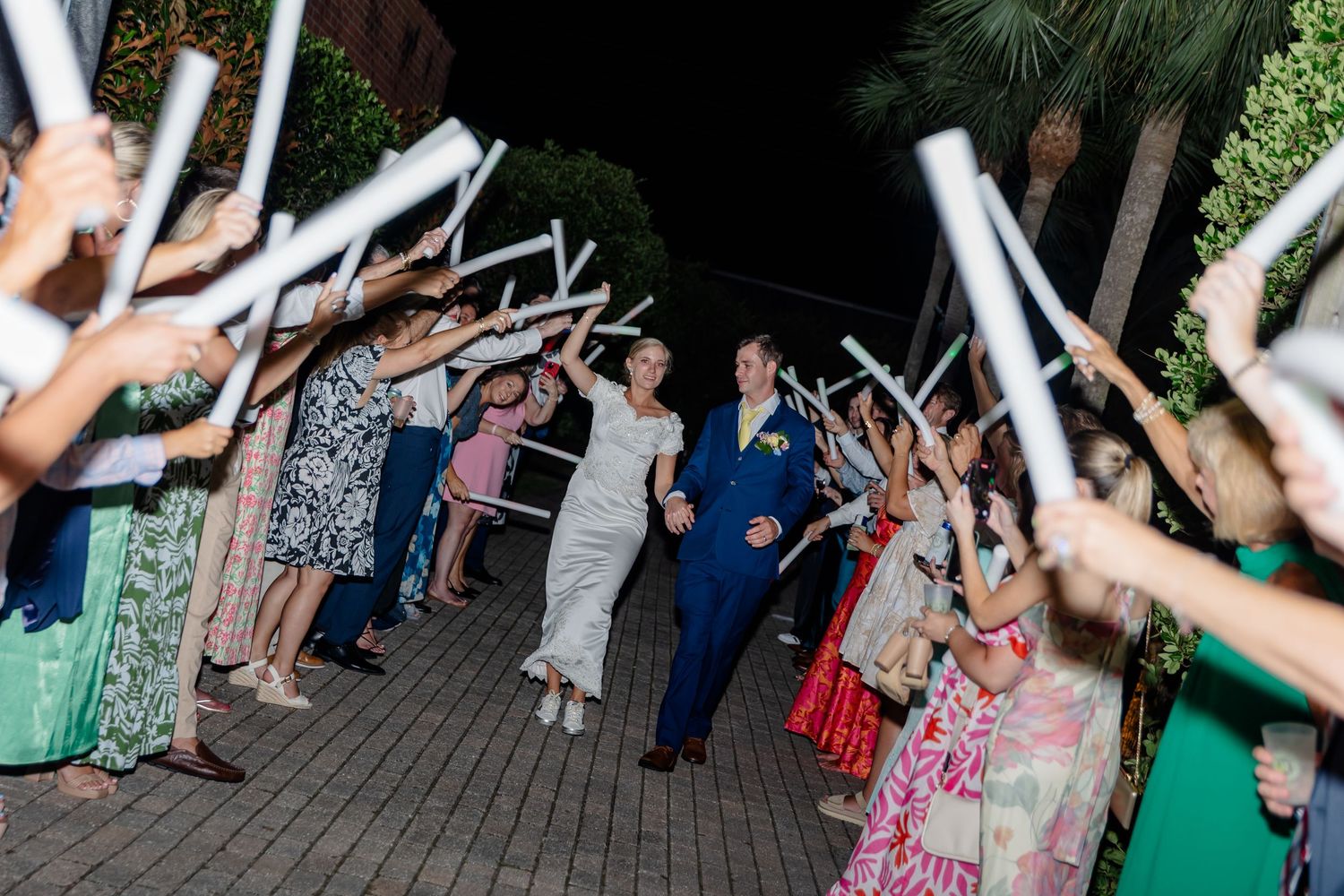 Wedding guests dance and celebrate on an outdoor deck during a lively reception party.