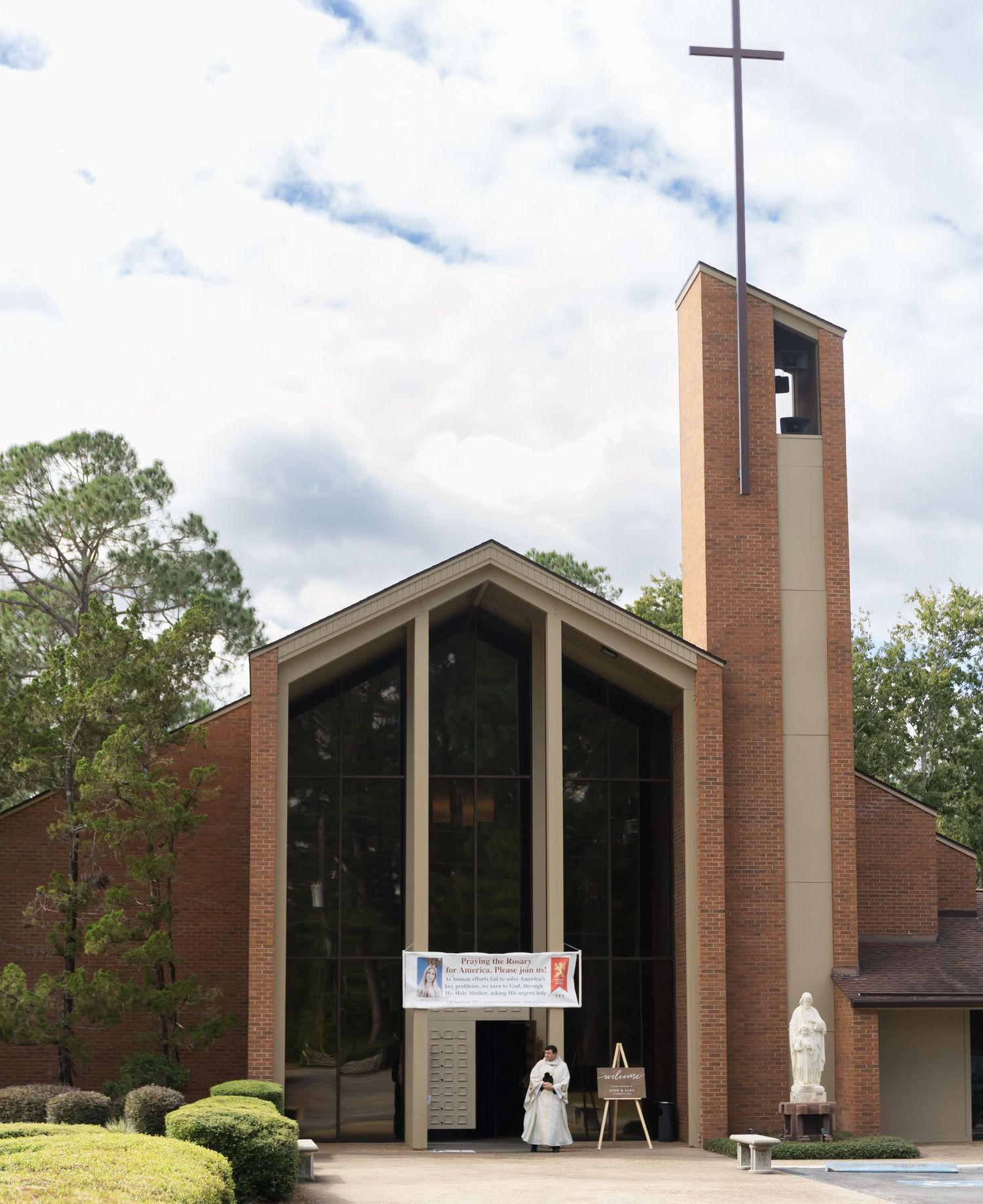 Modern brick church exterior with multiple angular towers and cross details against cloudy sky.