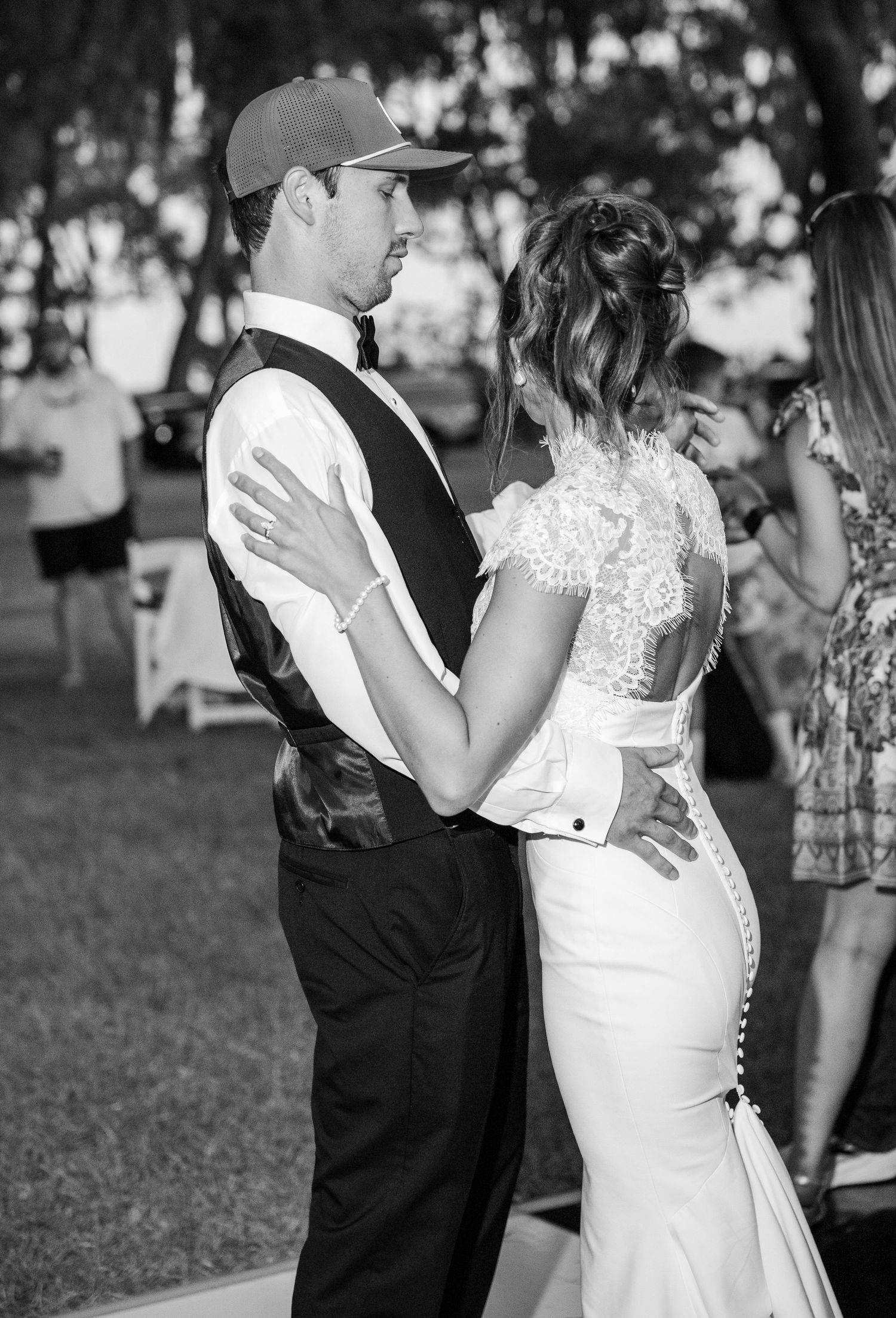 Black and white photo of a bride and groom sharing their first dance outdoors at a wedding reception.