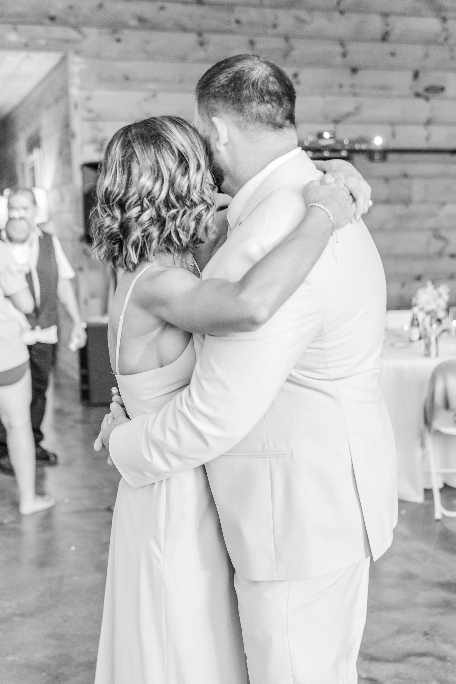 Black and white capture of a tender wedding dance moment in a rustic venue setting.