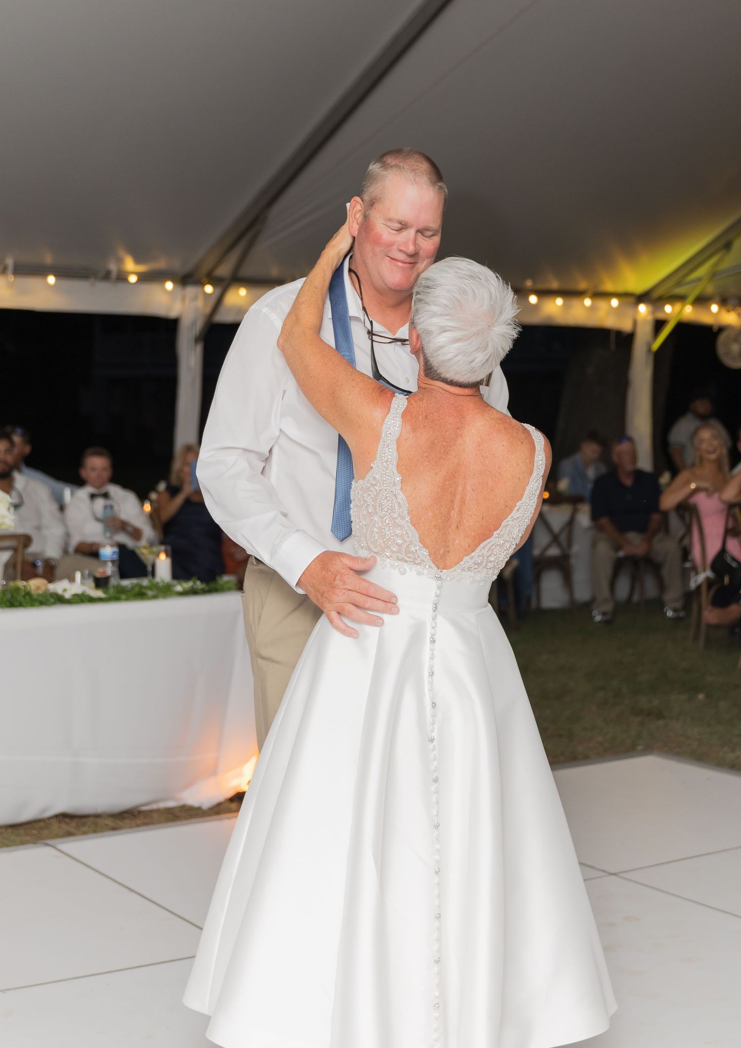 Couple shares an intimate dance moment at their wedding reception under a tent.
