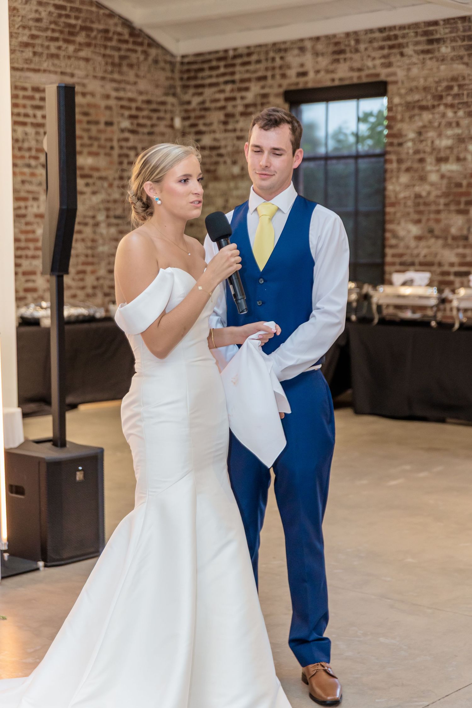 Wedding couple dancing together in an elegant industrial venue with exposed brick walls.