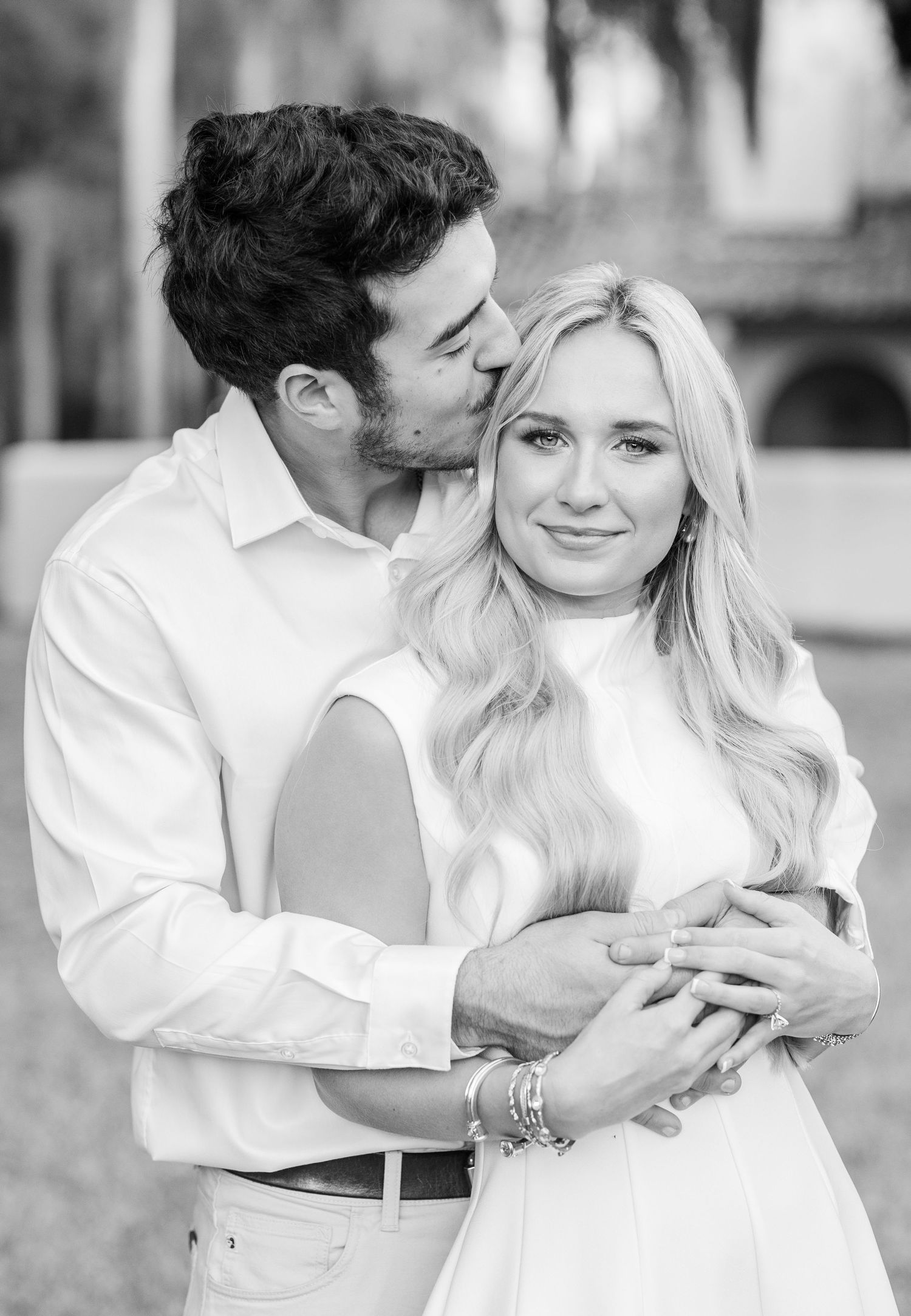 A romantic black and white photo series showing a couple embracing and sharing tender moments together outdoors.