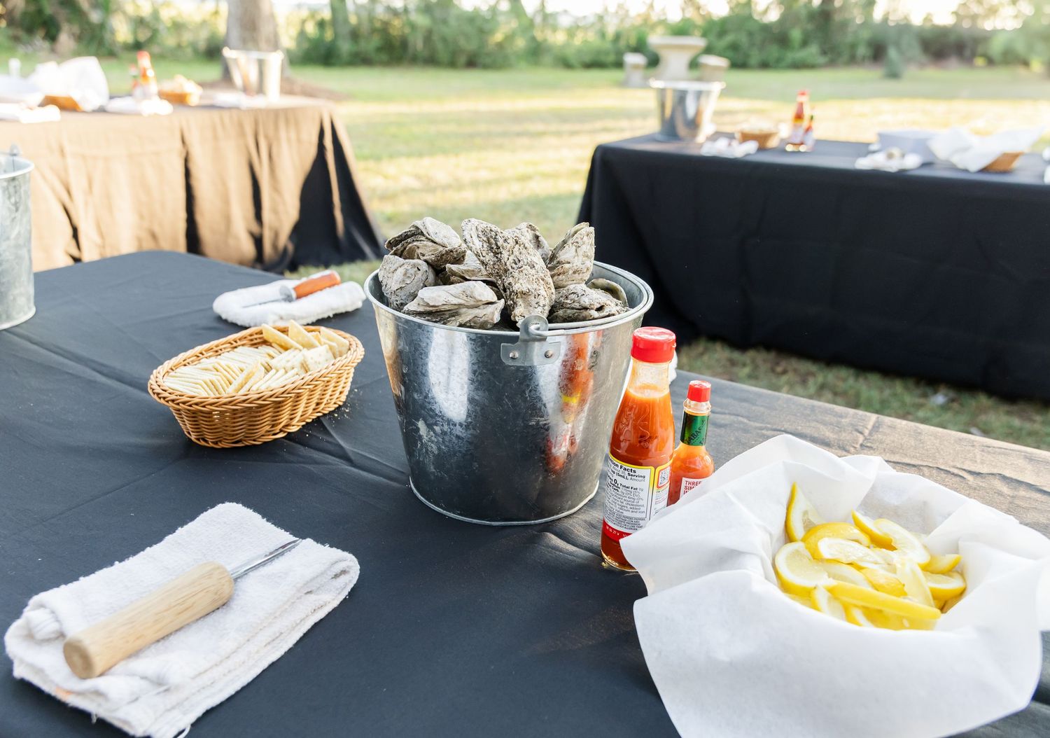 Casual outdoor buffet table with metal ice bucket, bread basket and condiments.