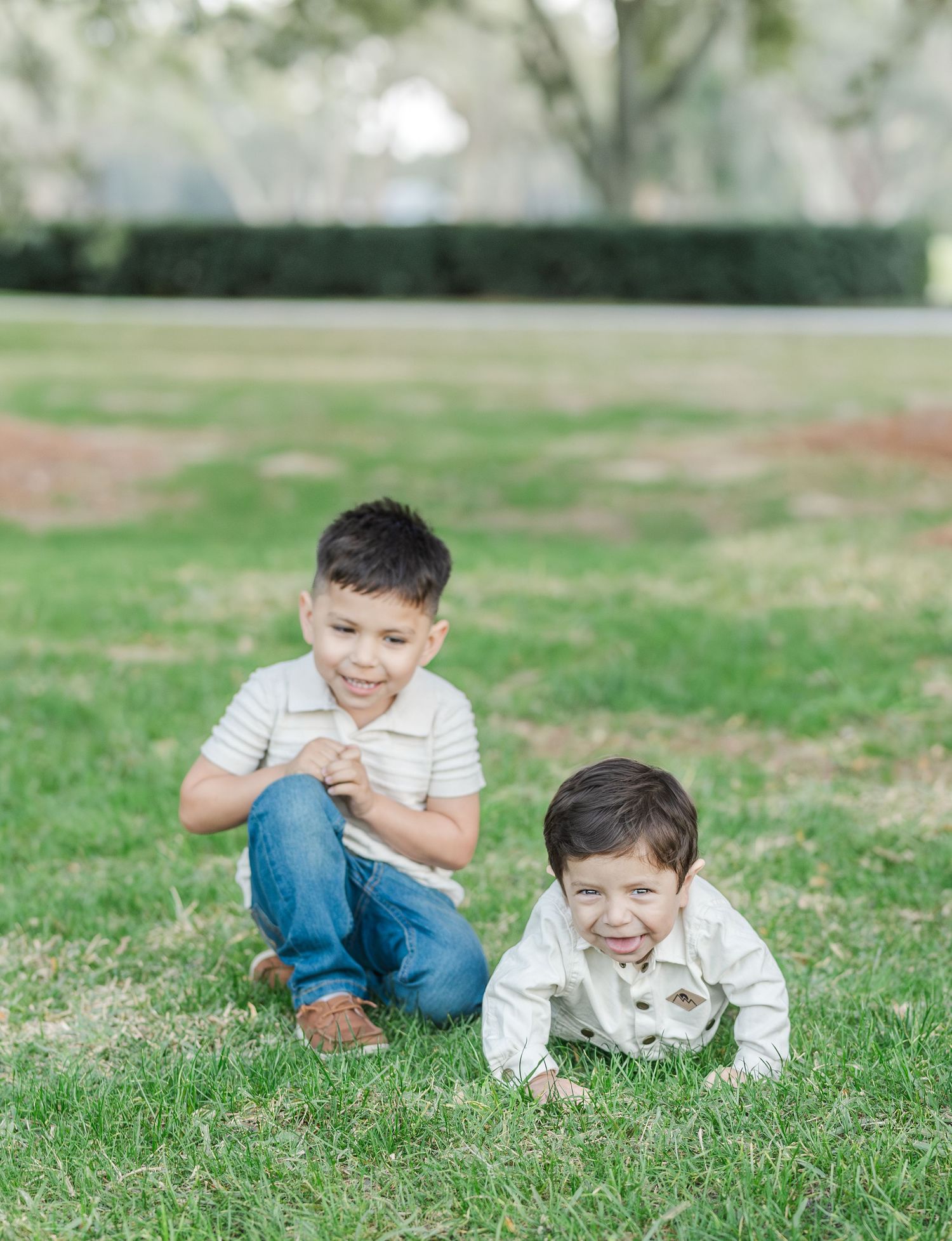 Young child lying on grass with a playful expression during outdoor photo session.