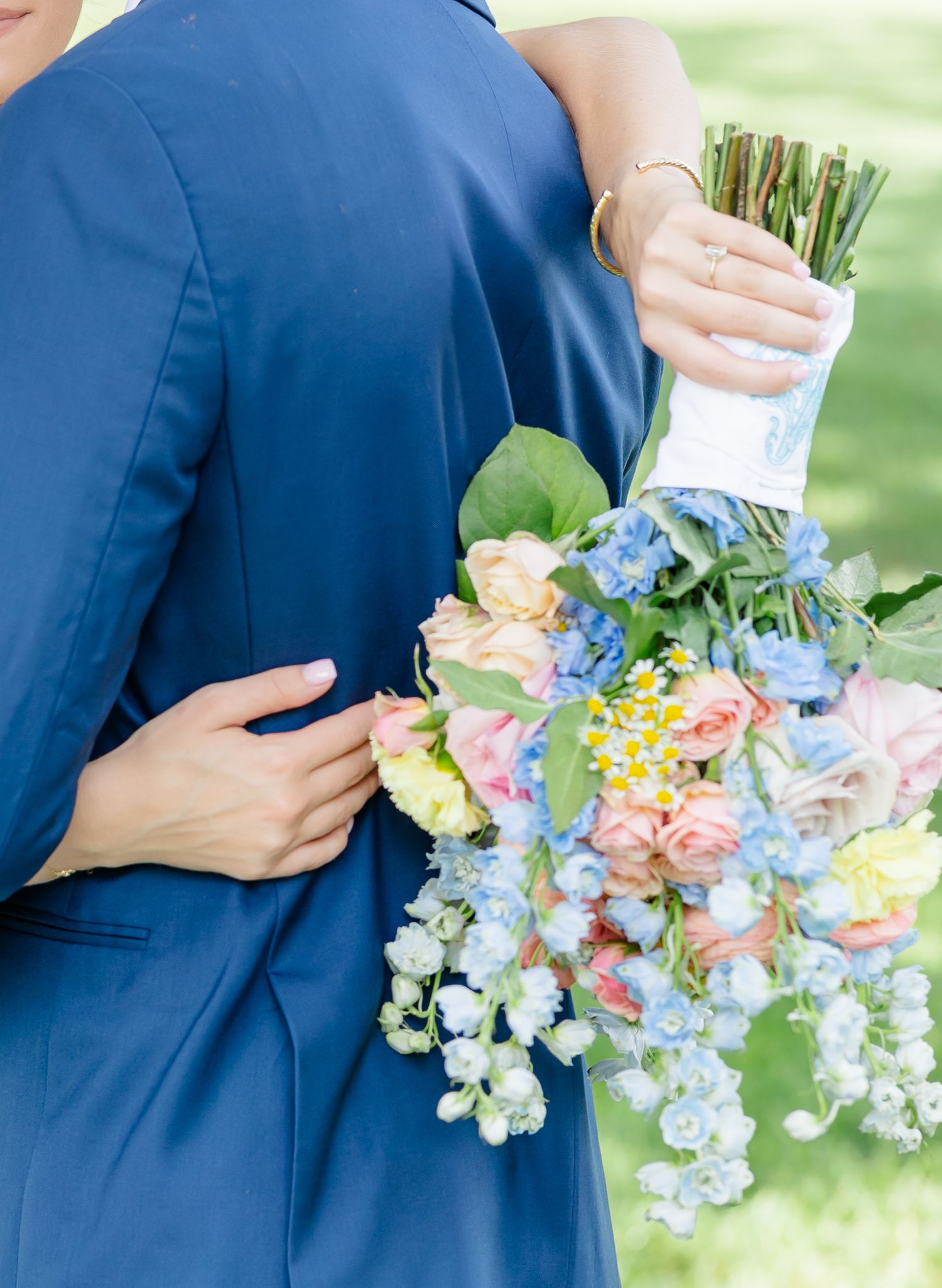 A close-up series showing hands holding delicate pastel floral bouquets against a navy blue formal attire background.