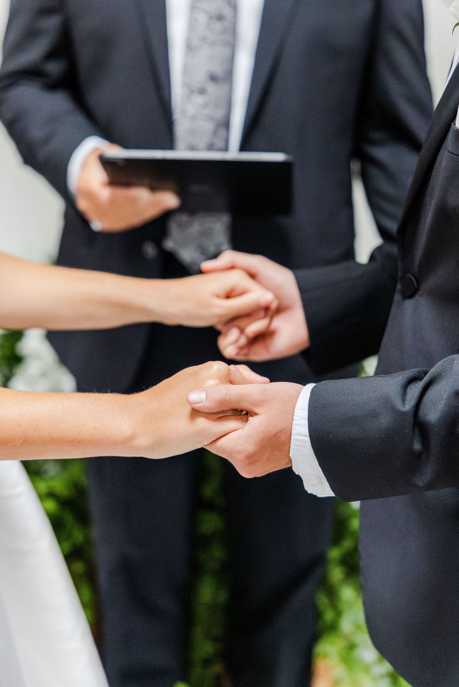 Close-up of bride and groom exchanging rings during wedding ceremony with officiant.