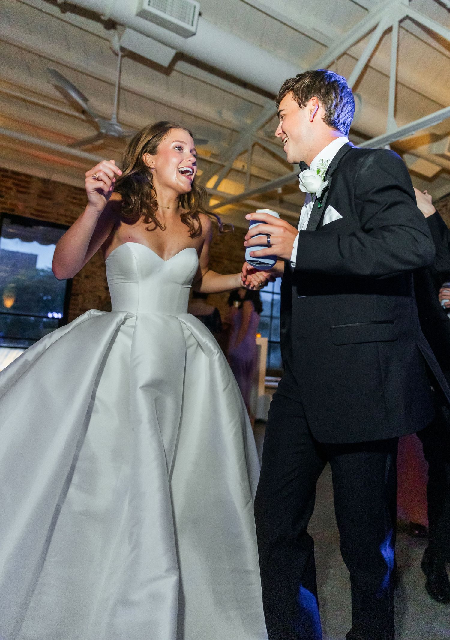 Laughing bride and groom enjoying an energetic dance at their wedding reception.