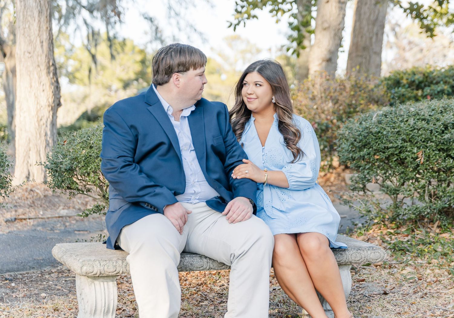 Couple in coordinated blue and white outfits sharing intimate moments during an outdoor photo session in a park.