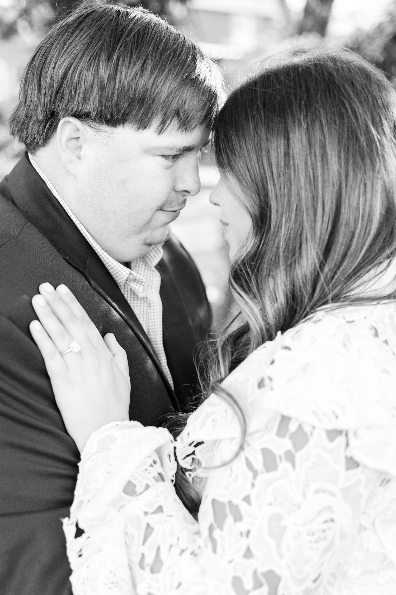An intimate black and white portrait of an engaged couple sharing a tender moment.