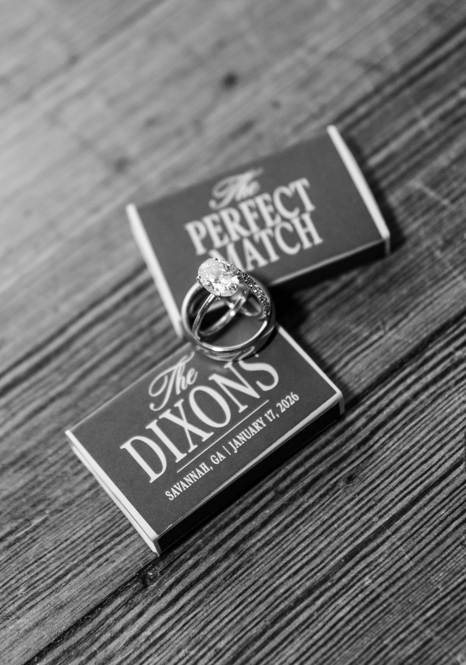 Wedding rings placed on black and white chocolate bar wrappers on a rustic wooden surface.