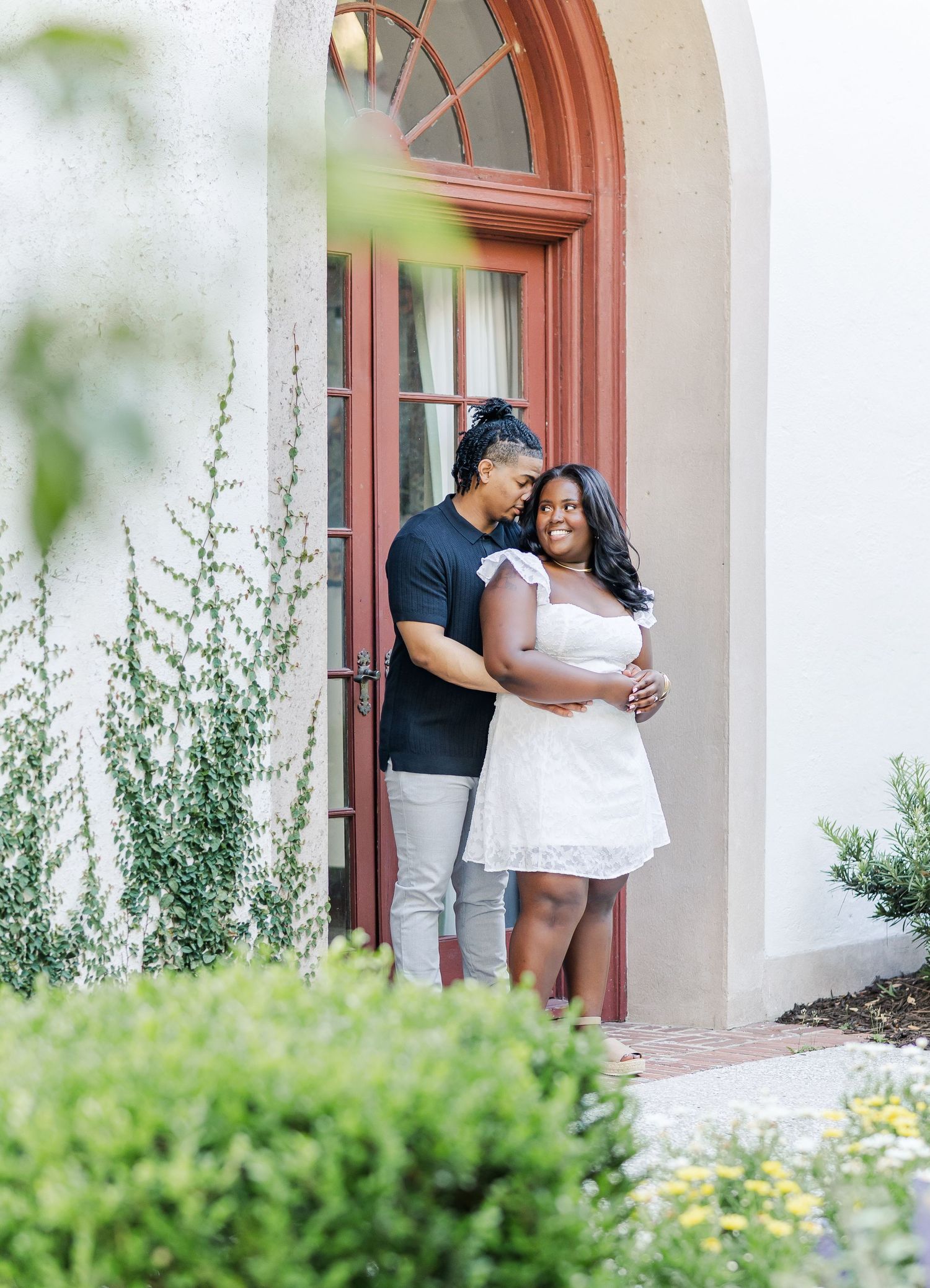 Sweet engagement photos captured in front of an elegant arched doorway.