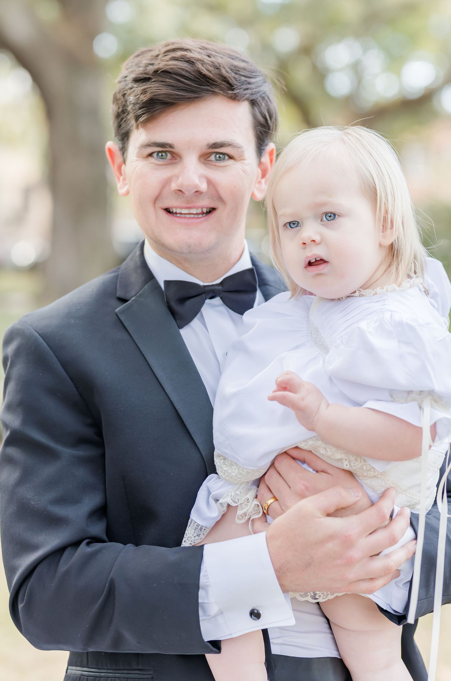 Formal wedding portraits with small child in white outfit.