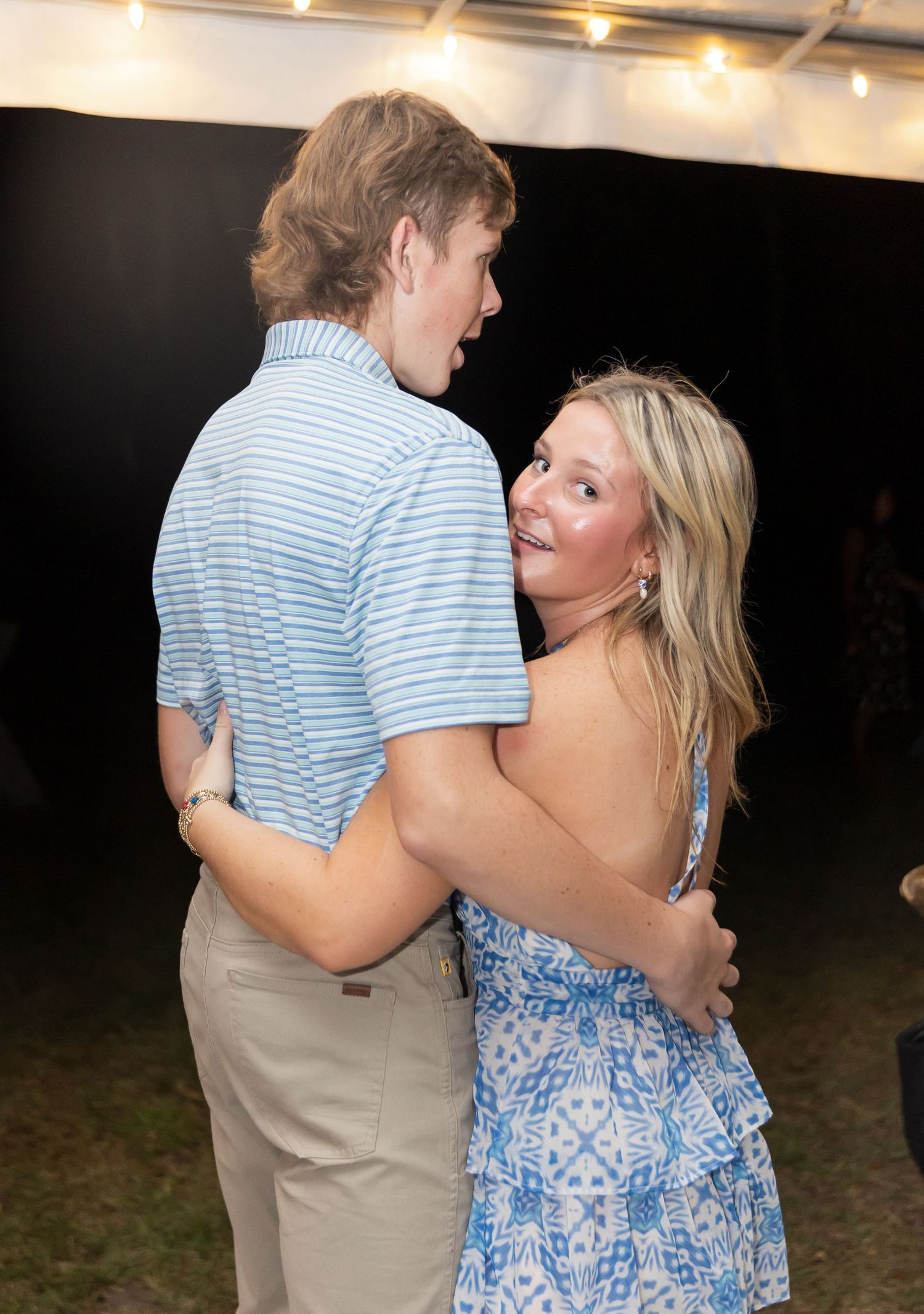 Guests in summer attire dancing together at a nighttime outdoor celebration.