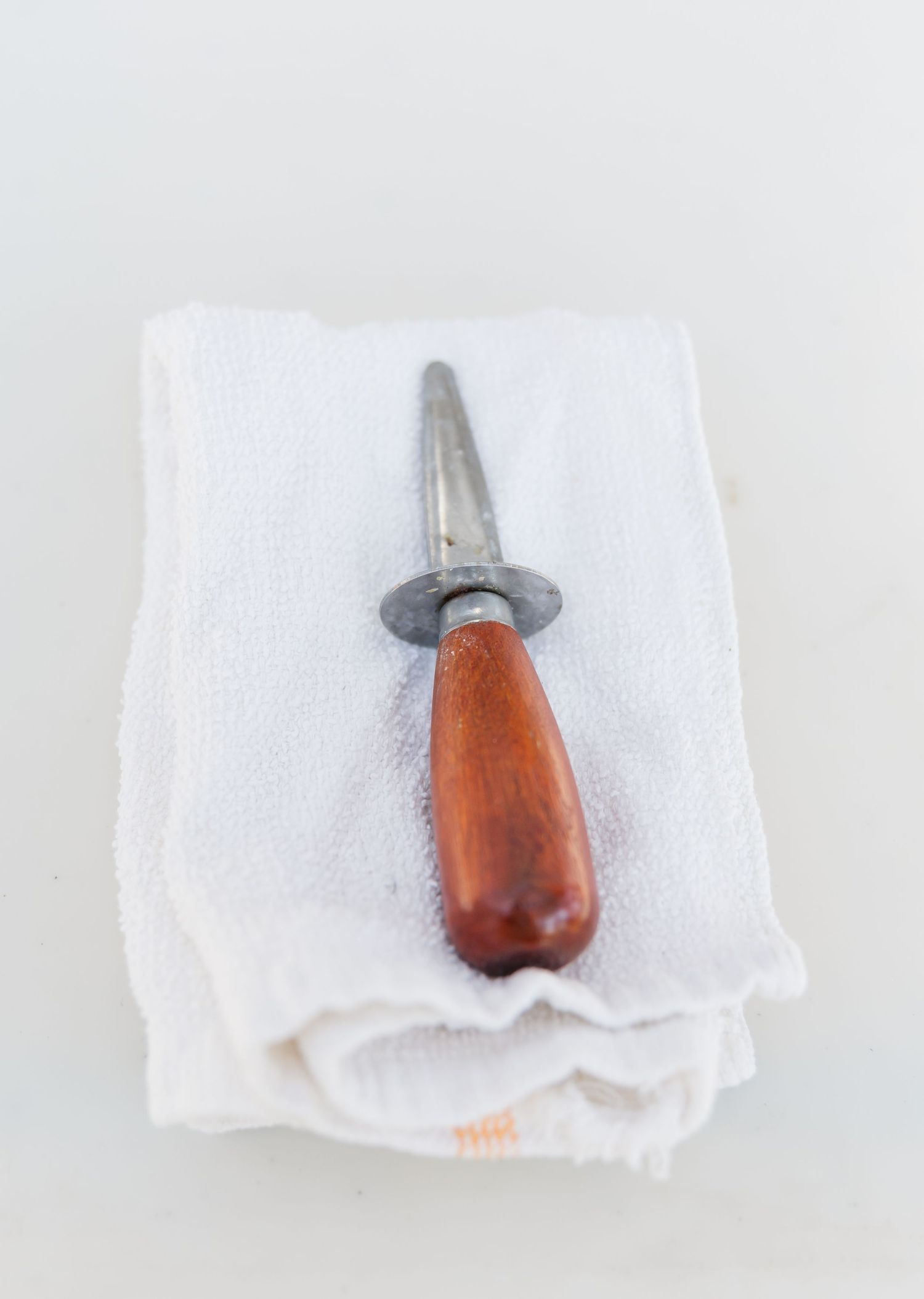 Four identical tools with wooden handles and metal tips arranged in a row on white napkins.