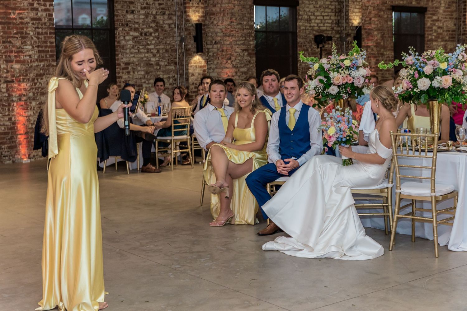 Wedding reception scene in an industrial-style venue with exposed brick walls and elegant decor.