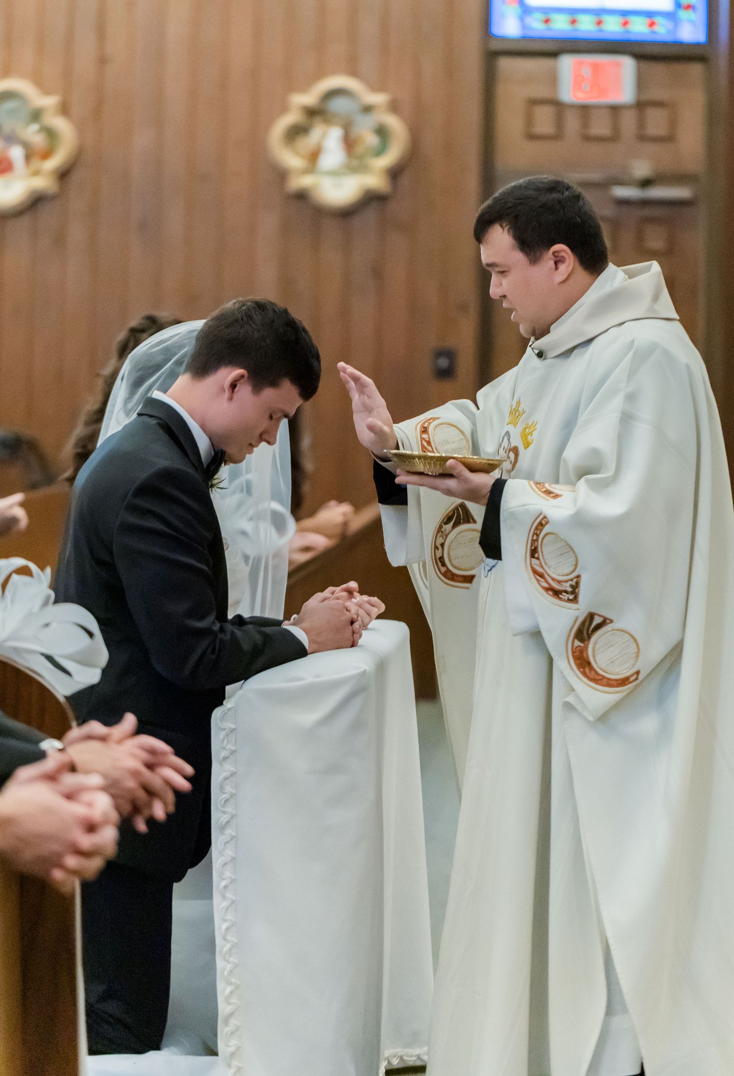 Row of clergy members in white robes and dark suits during religious ceremony.
