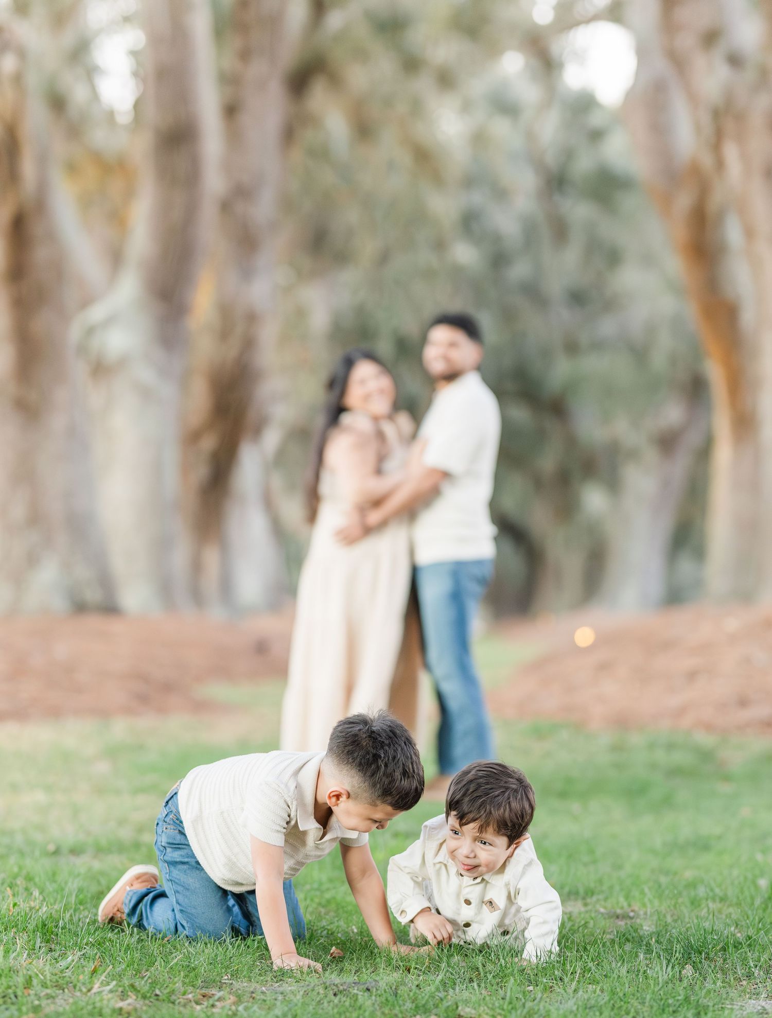 Candid family moments captured while playing and rolling on grassy hillside.