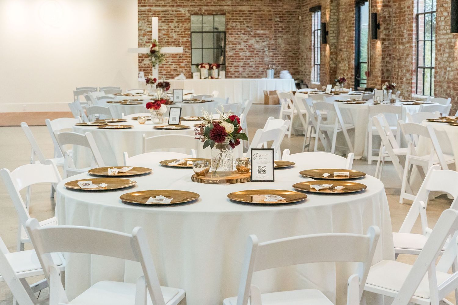 Wedding reception venue with exposed brick walls and white table settings.