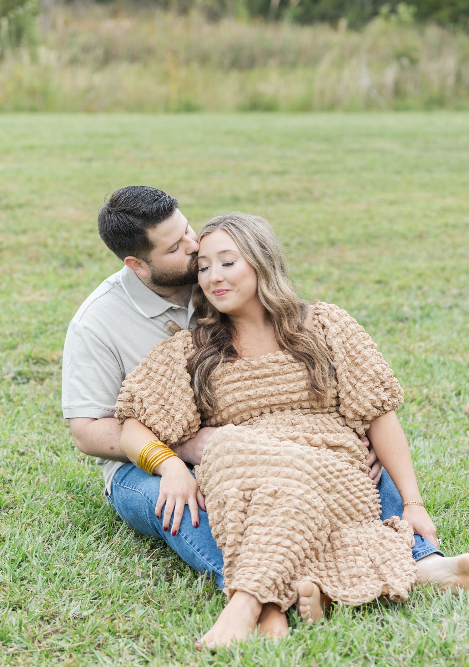Couple relaxes together on grass in a romantic outdoor photoshoot.