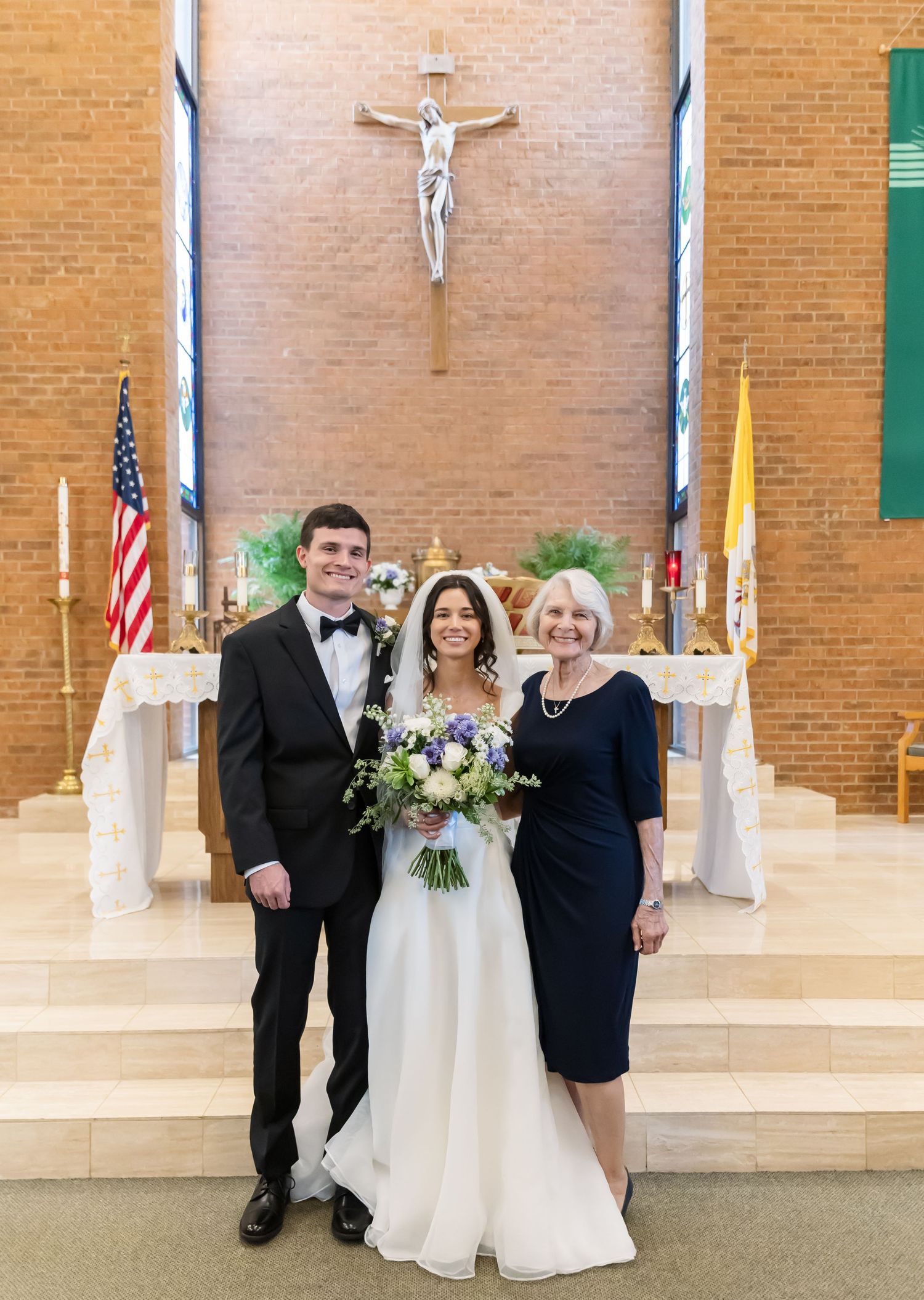 Wedding ceremony photo in a church with crucifix and American flag in background.