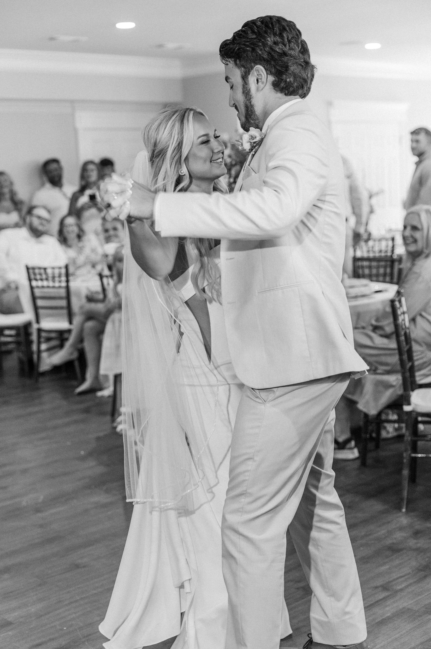 Black and white photo of bride and groom sharing romantic first dance at wedding reception.