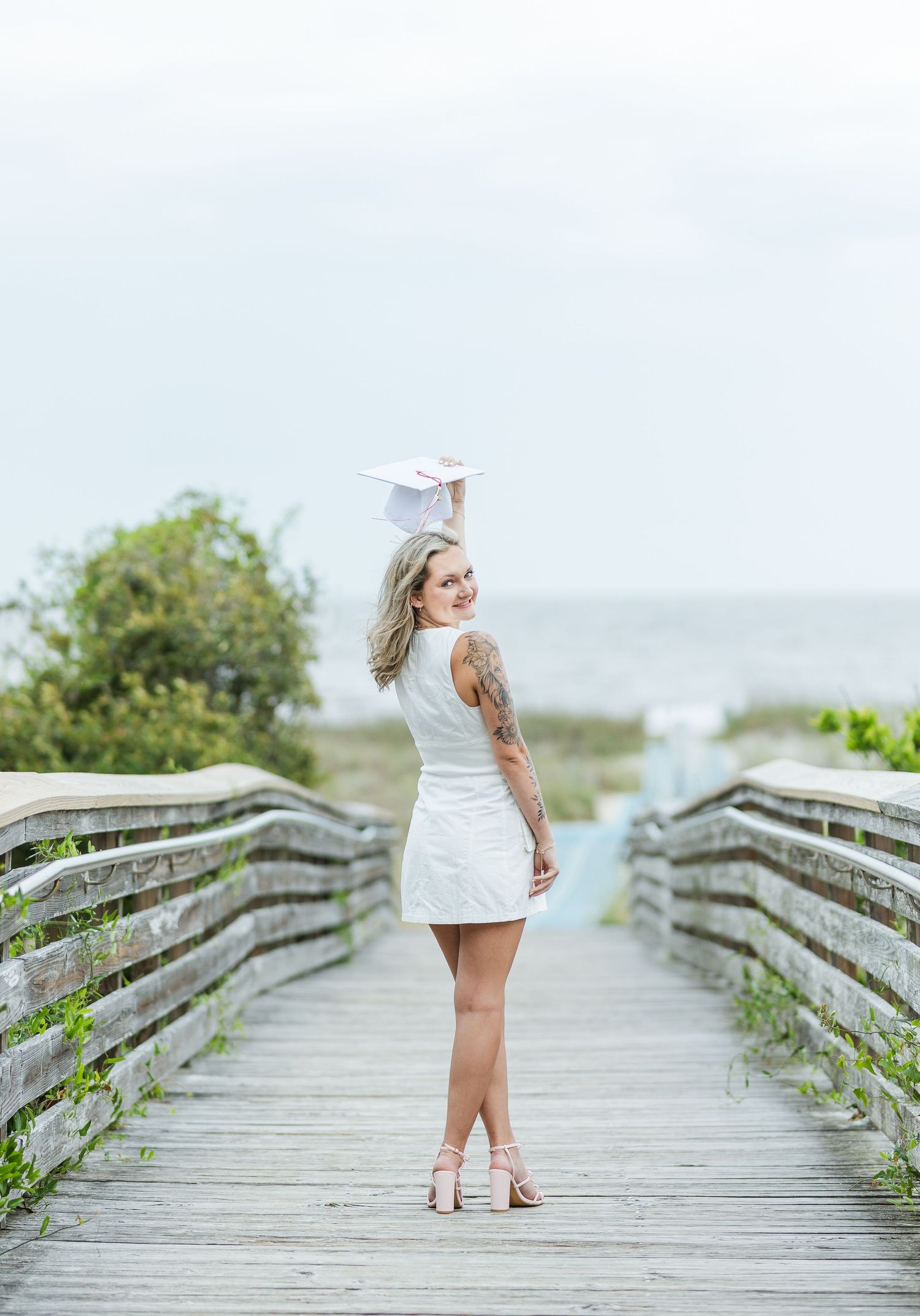 Coastal boardwalk scene with white dress and gentle ocean breeze creating a dreamy atmosphere.
