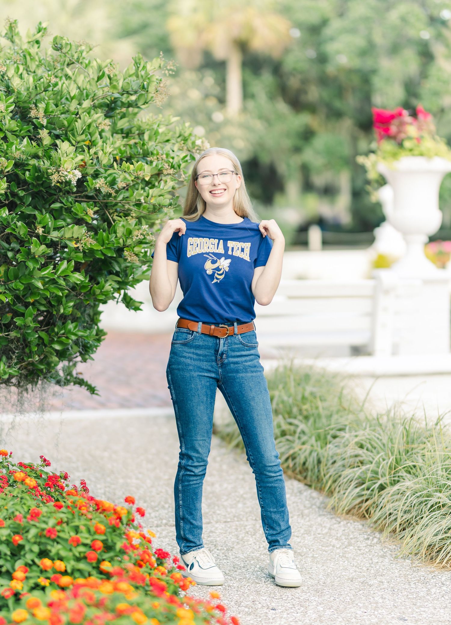 A sequence of candid outdoor portraits showing someone in a blue shirt and jeans walking along a garden path with flowers.
