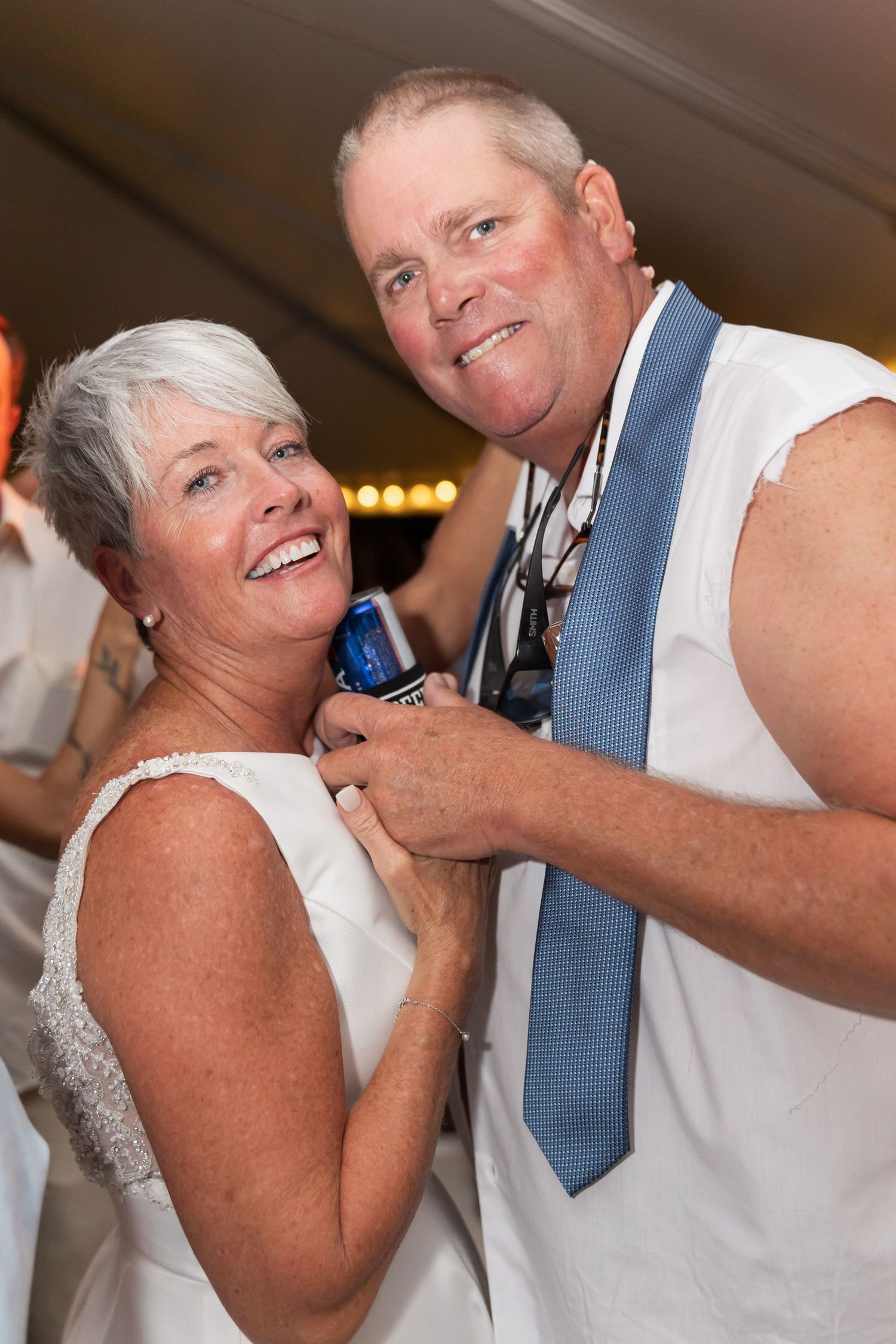 Wedding guests sharing drinks and laughter during an outdoor reception celebration.