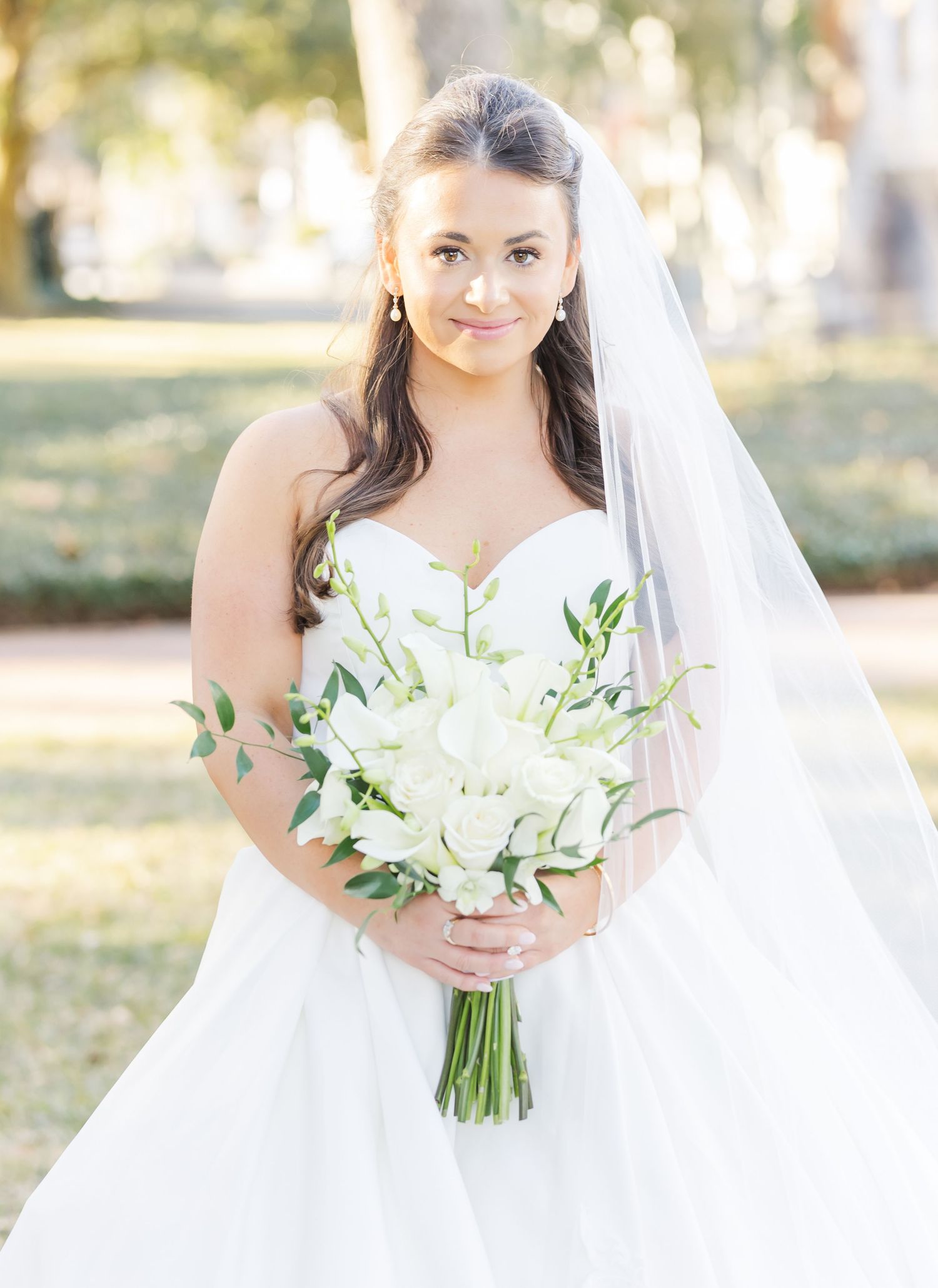 Elegant bridal portraits featuring a white wedding gown, veil, and classic white bouquet in natural lighting.