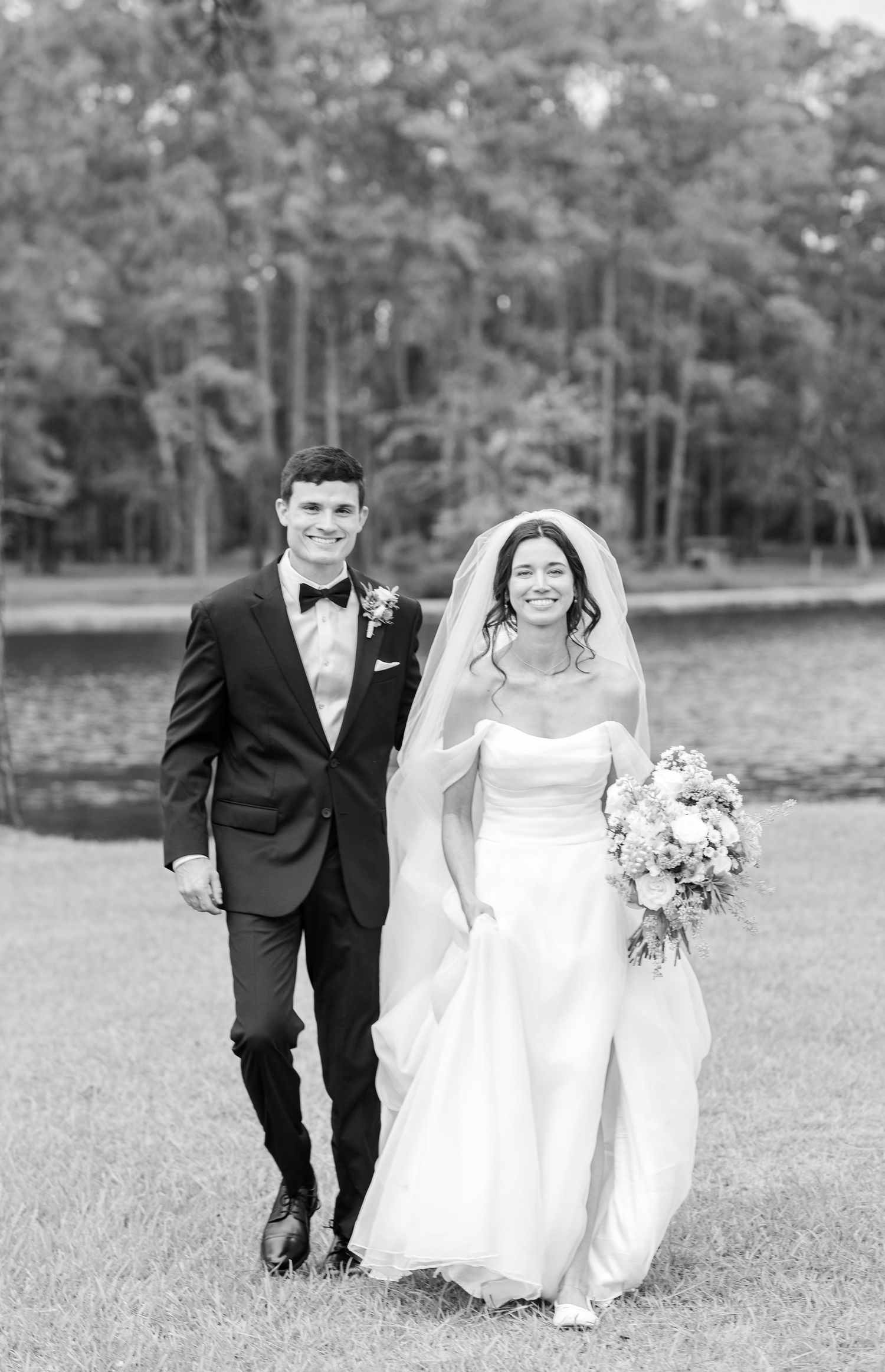 A black and white photo series of a couple walking together in formal wedding attire across a grassy field.