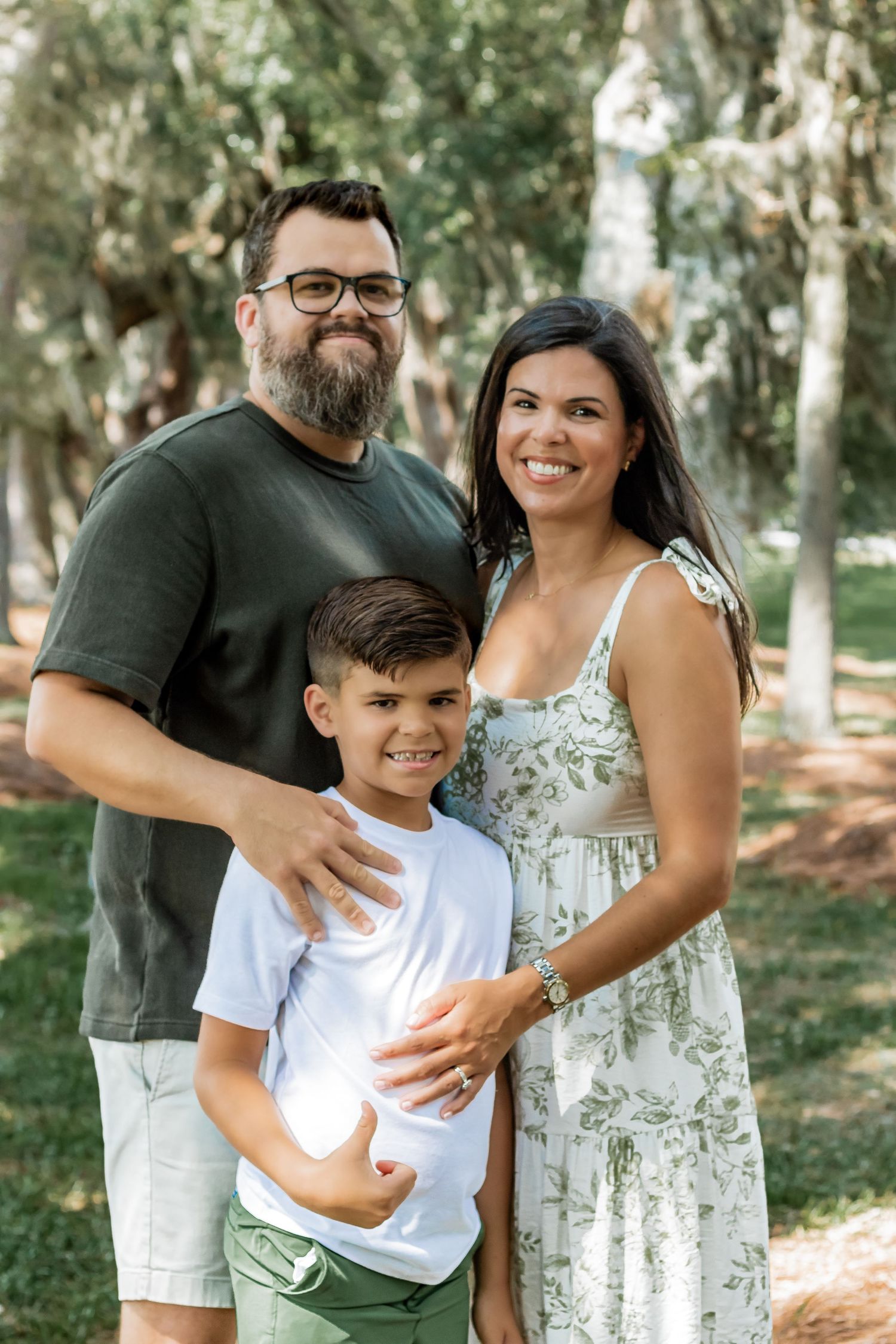 Family portrait under Spanish moss-draped trees in a peaceful park setting.