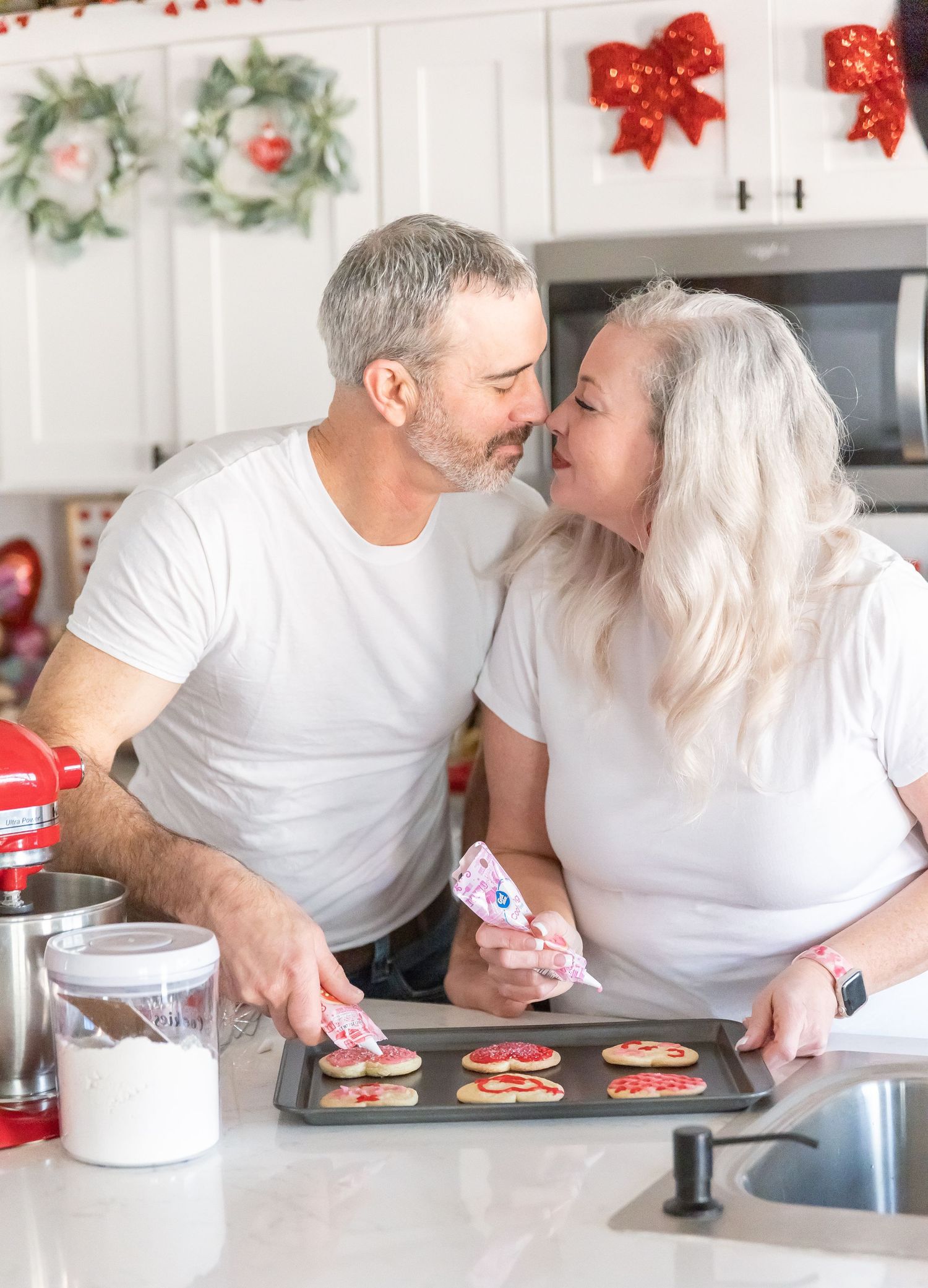 Partners working together on decorating festive cookies while sharing intimate moment.