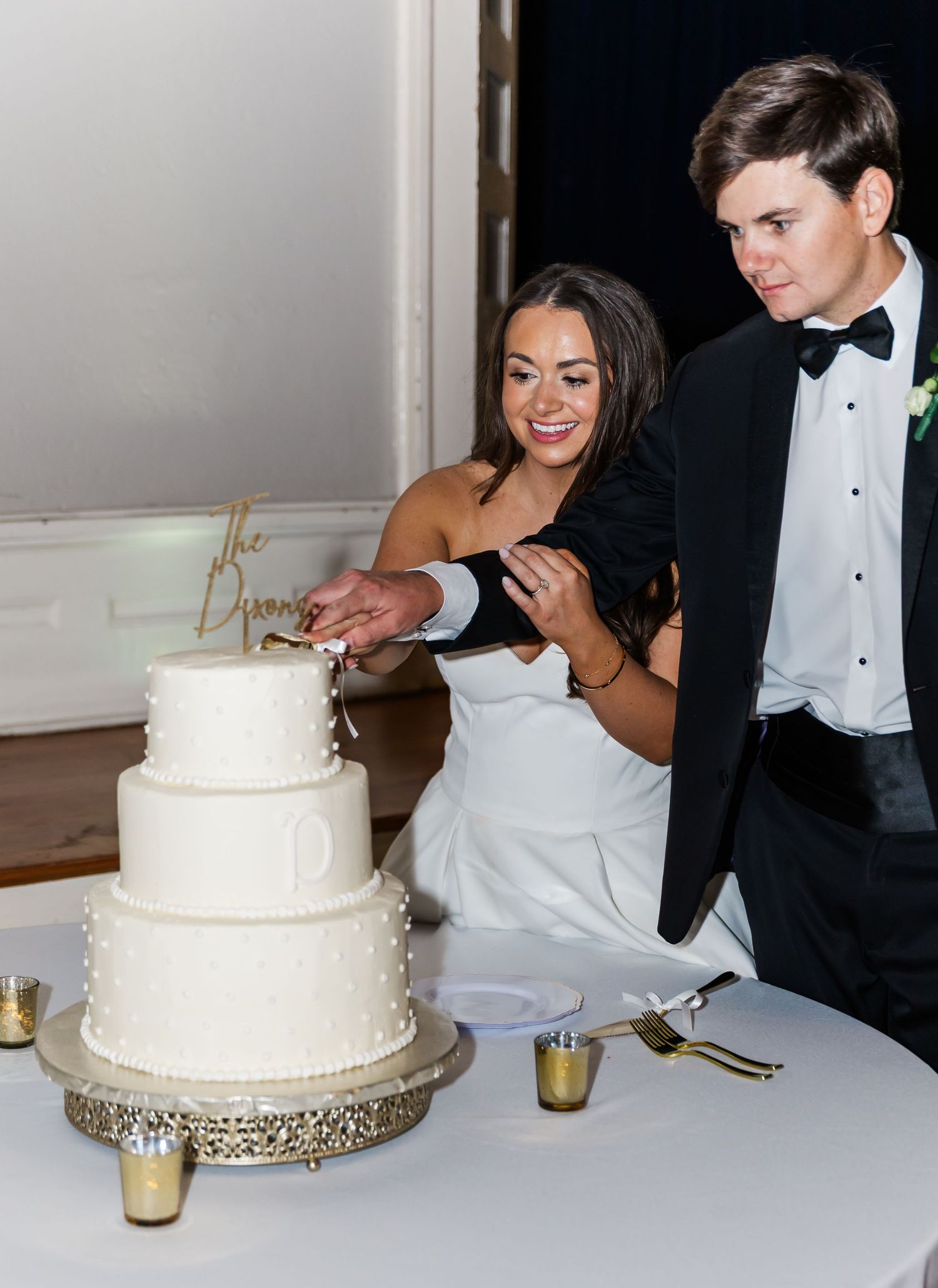 Bride and groom cutting their three-tier white wedding cake at their elegant reception.