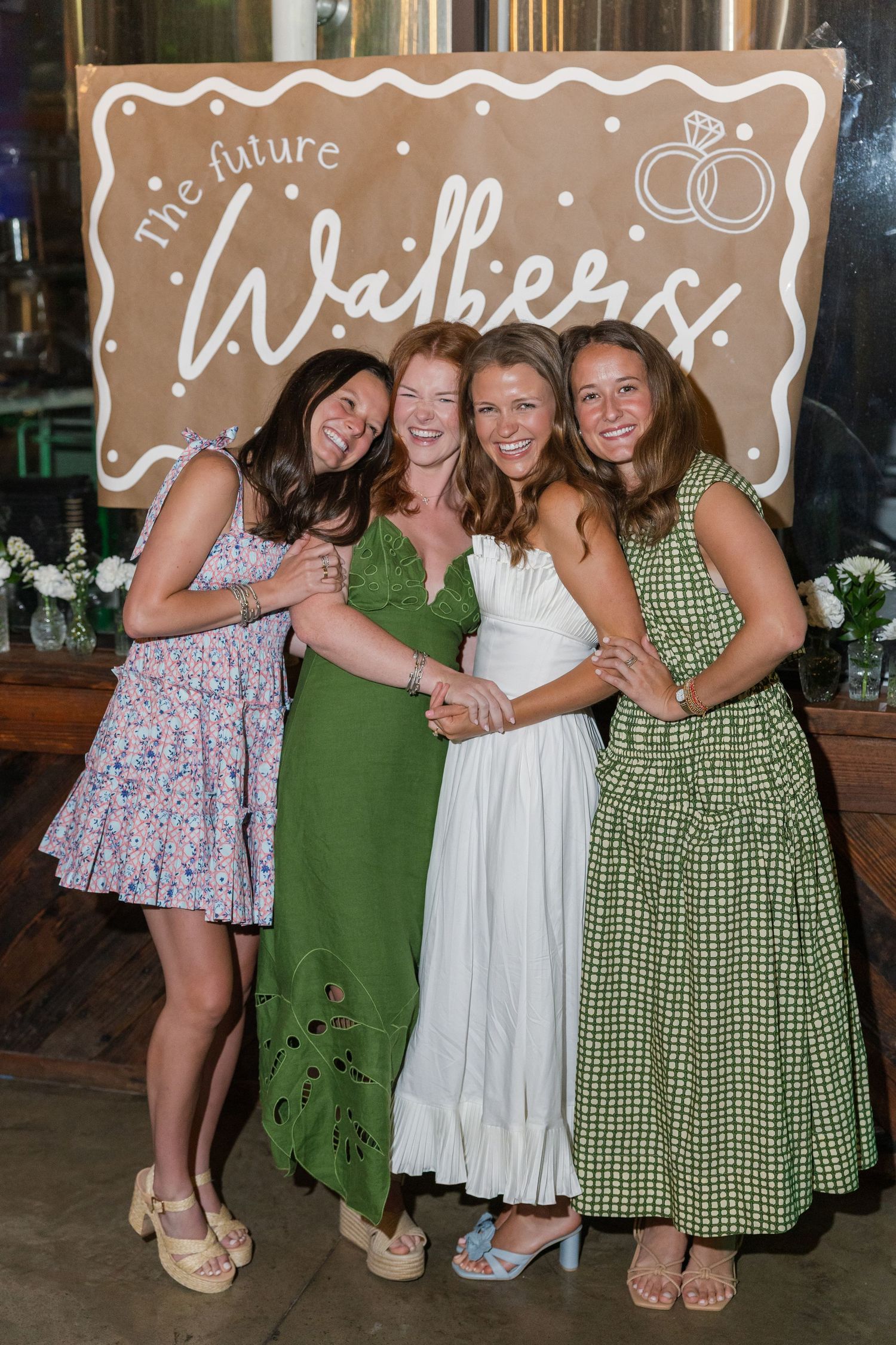 Four women smiling together at a bridal shower in front of a The Future Walkers sign.