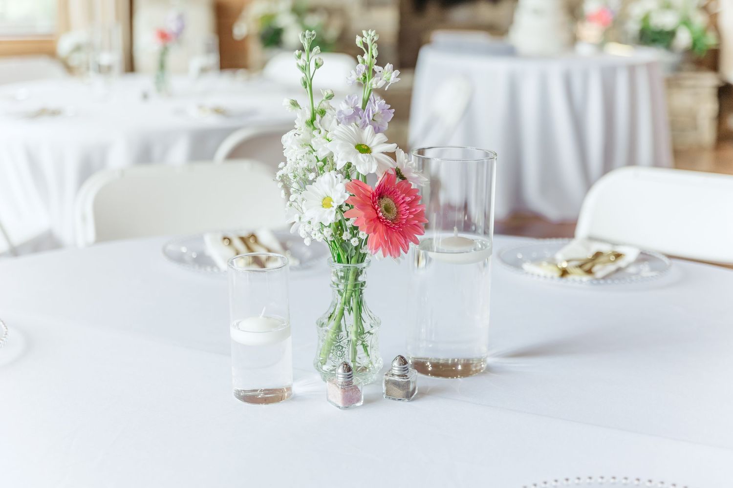 Elegant table setting with pink gerbera daisy centerpiece and gold cutlery.